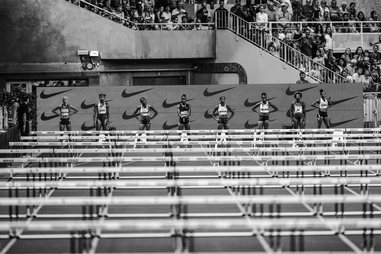 Black & White photograph of the starting line-up of a women's hurdles race.