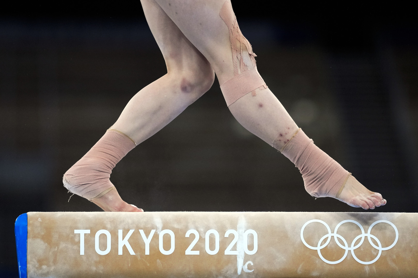 Gymnasts legs moving across a beam at the Tokyo 2020 Olympics.