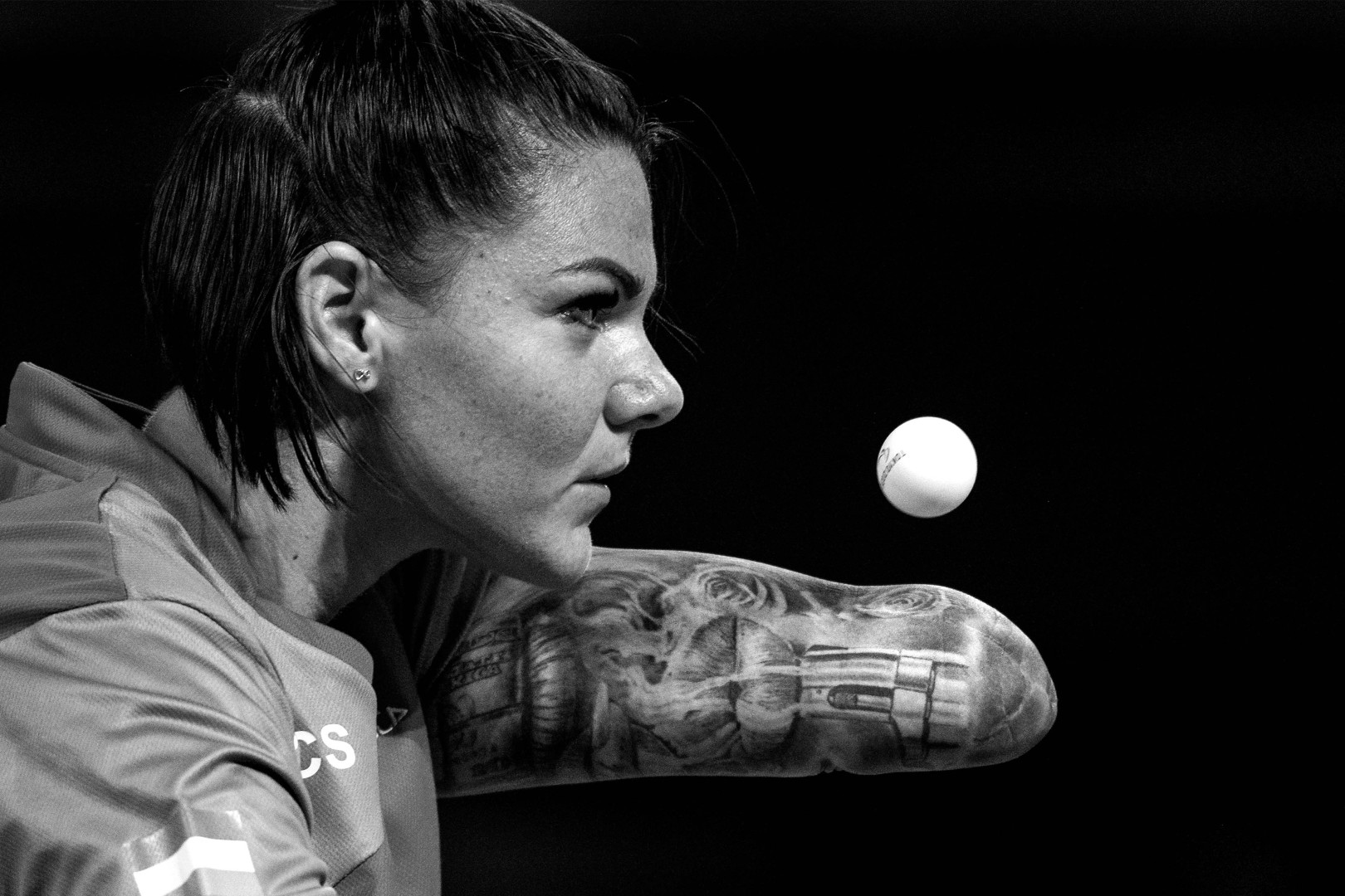 Black & White photograph of Paralympic table tennis player throwing table tennis ball.