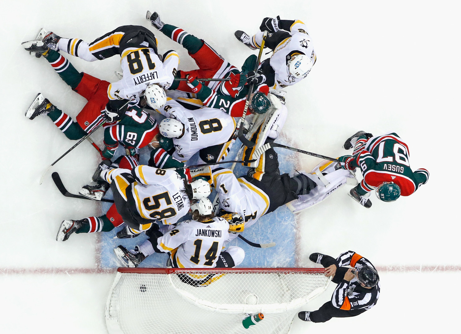 Scrum of ice hockey players on the rink in front of goal.