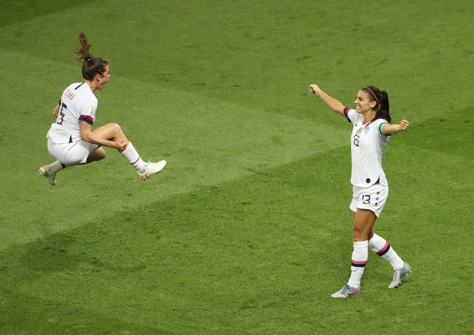 Kelley O'Hara celebrating by jumping in the air as she's joined by Alex Morgan.
