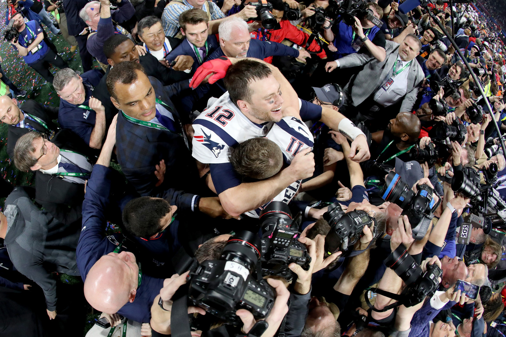 Super Bowl players celebrating whilst surrounded by security and paparazzi.