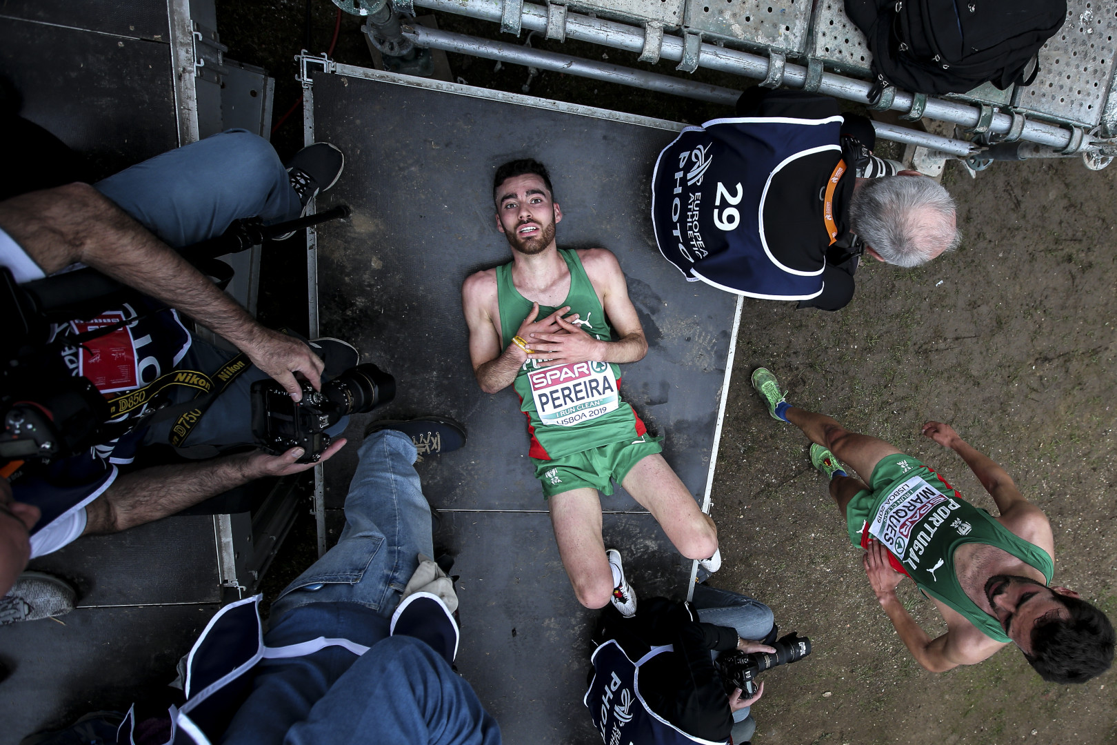 Birdseye view photograph of runner collapsed on stage after finishing a race.