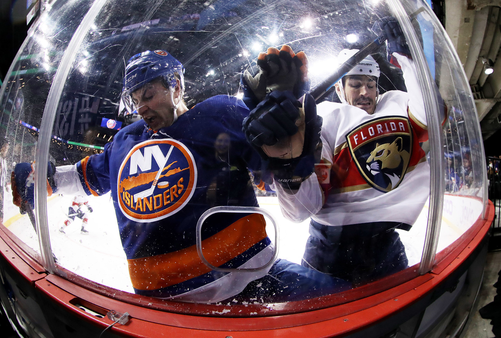 Fisheye photograph of two hockey players colliding with safety glass.