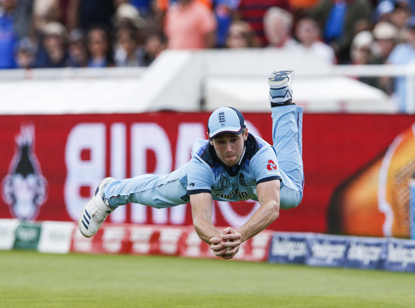 Chris Woakes diving to catch a cricket ball.