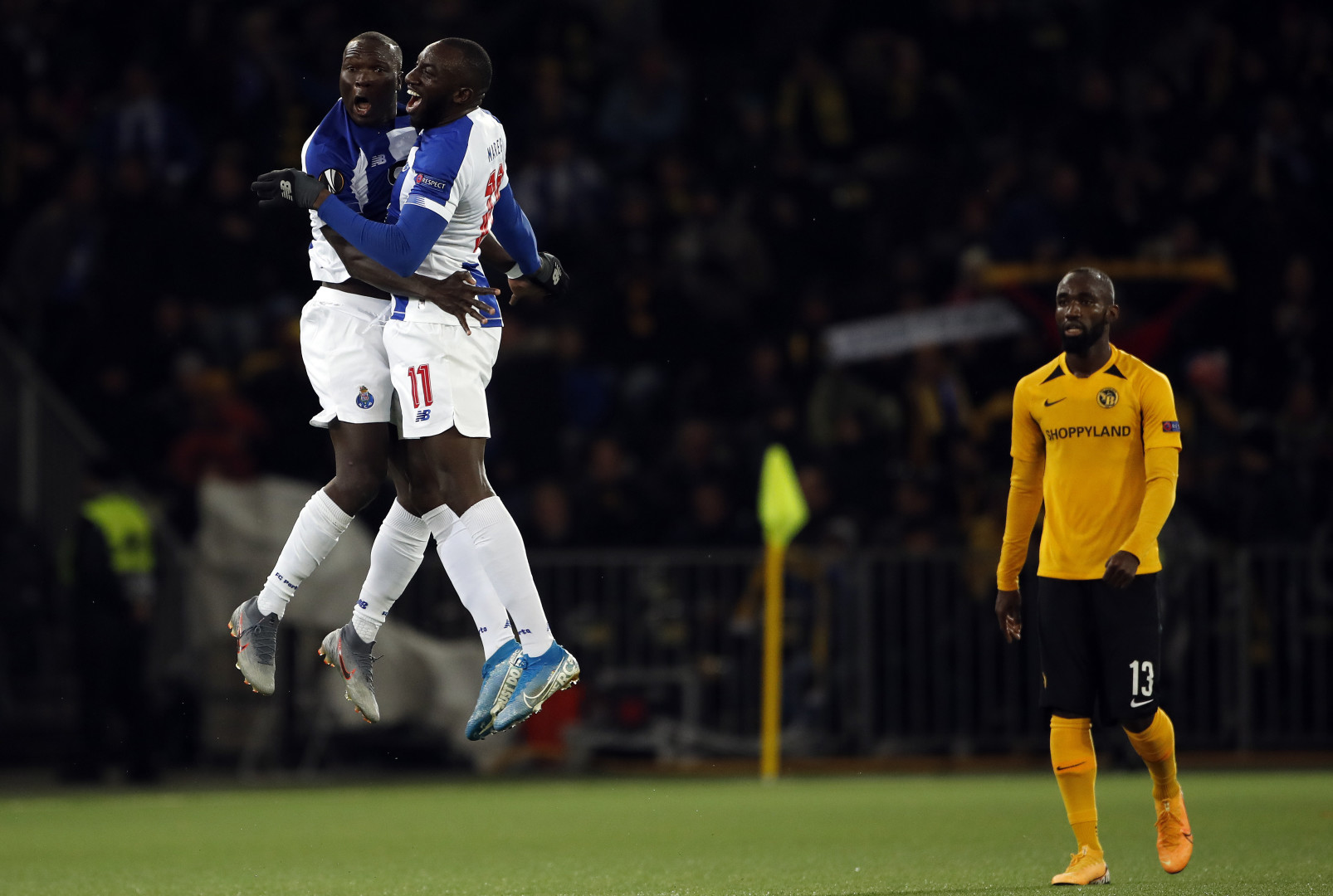 Two football players bumping chests mid air, celebrating a goal.
