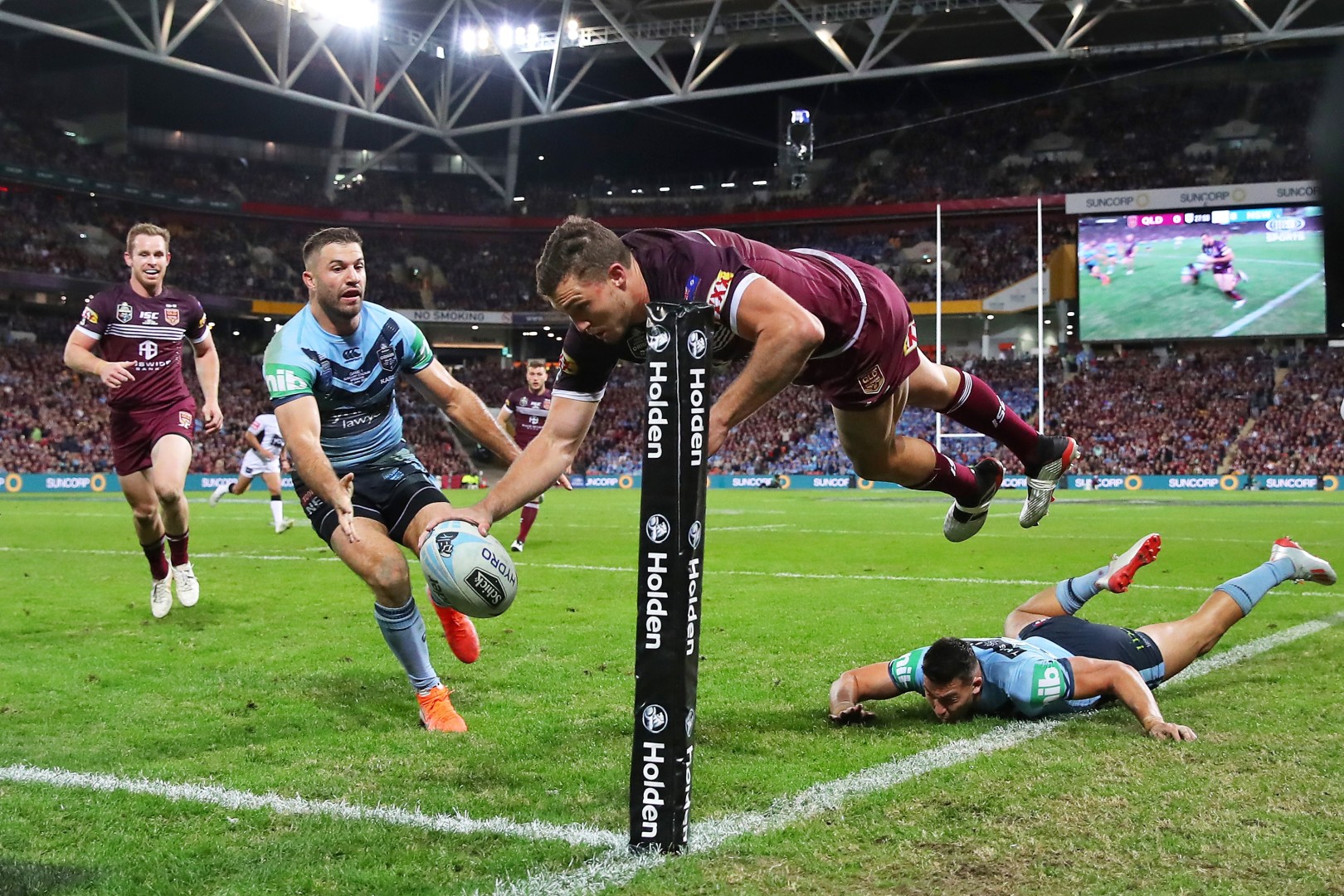 Rugby player midair centimetres from making a try whilst one opponent player is left flawed and the other racing to stop the try.