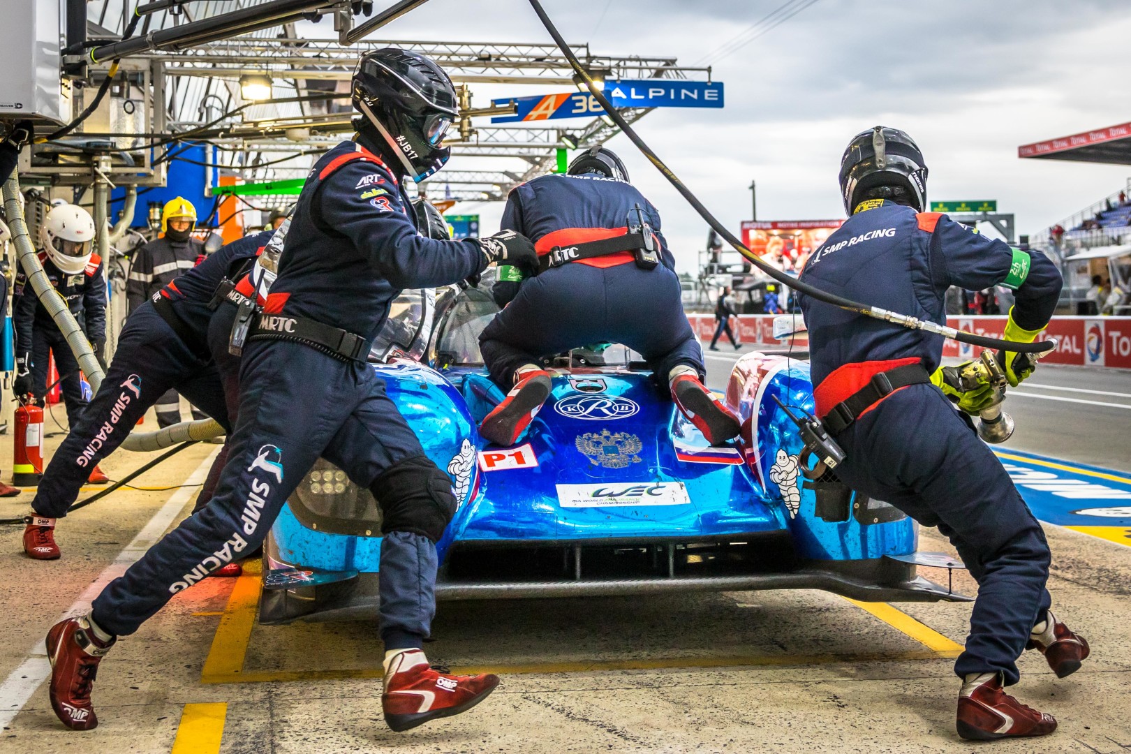 Motor sport pit stop team rushing to carry out maintenance on the race car.