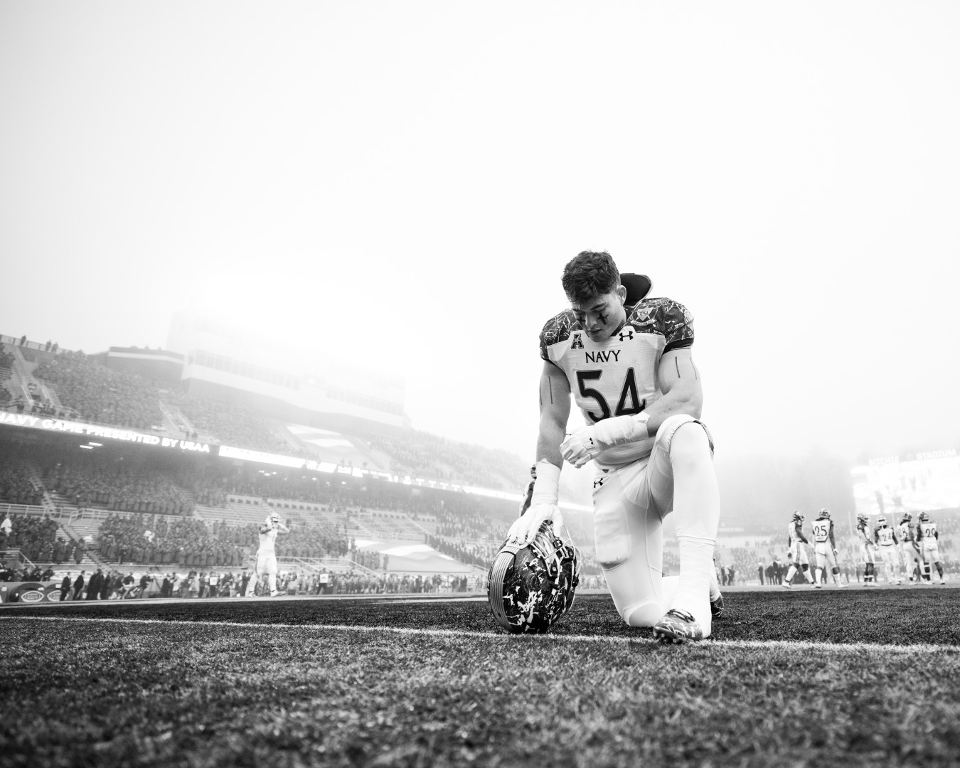 Black & White photograph of player placing down the American football at the centre of the pitch.