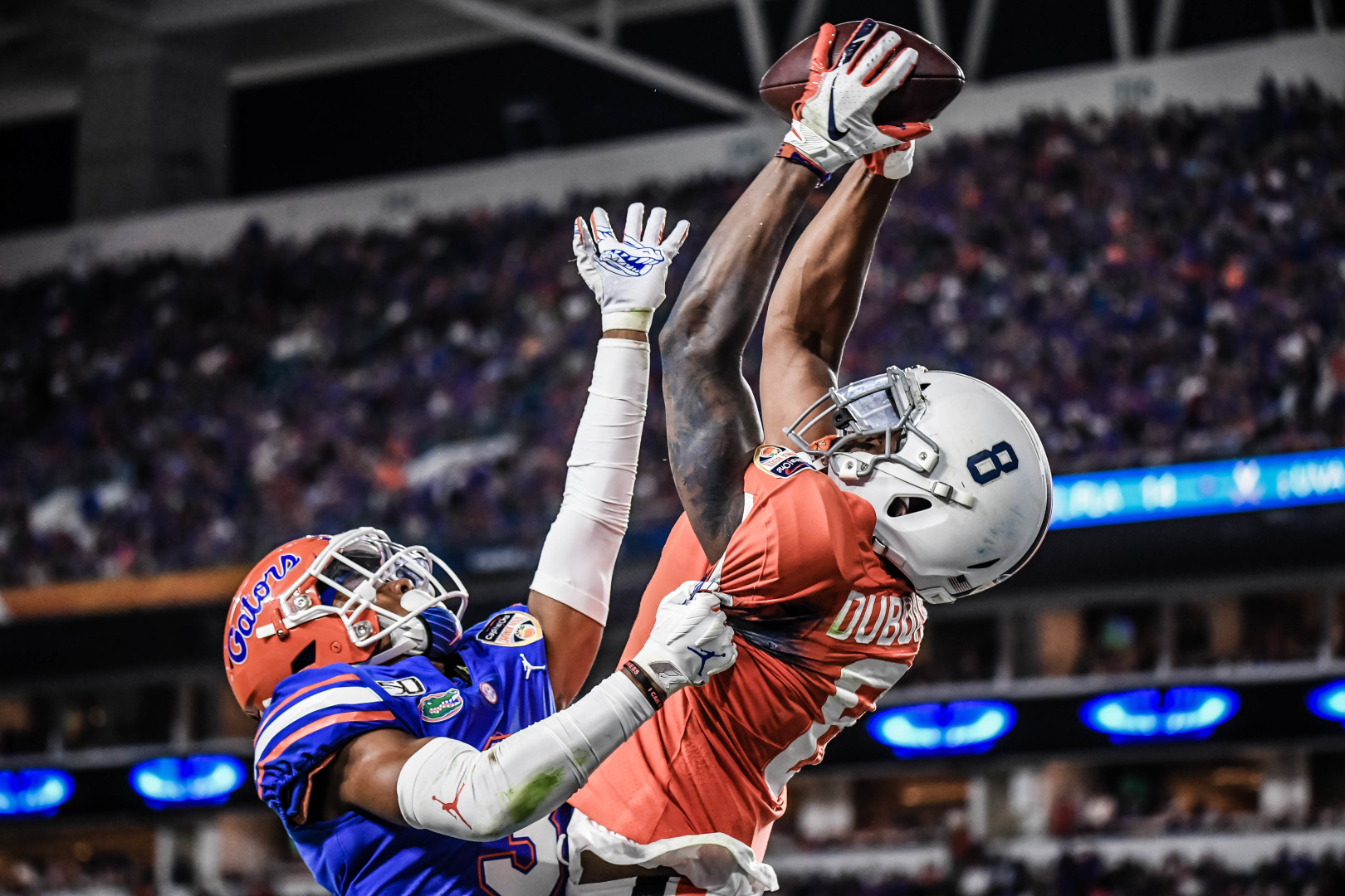 Two opposing players jumping and reaching high to catch the ball.