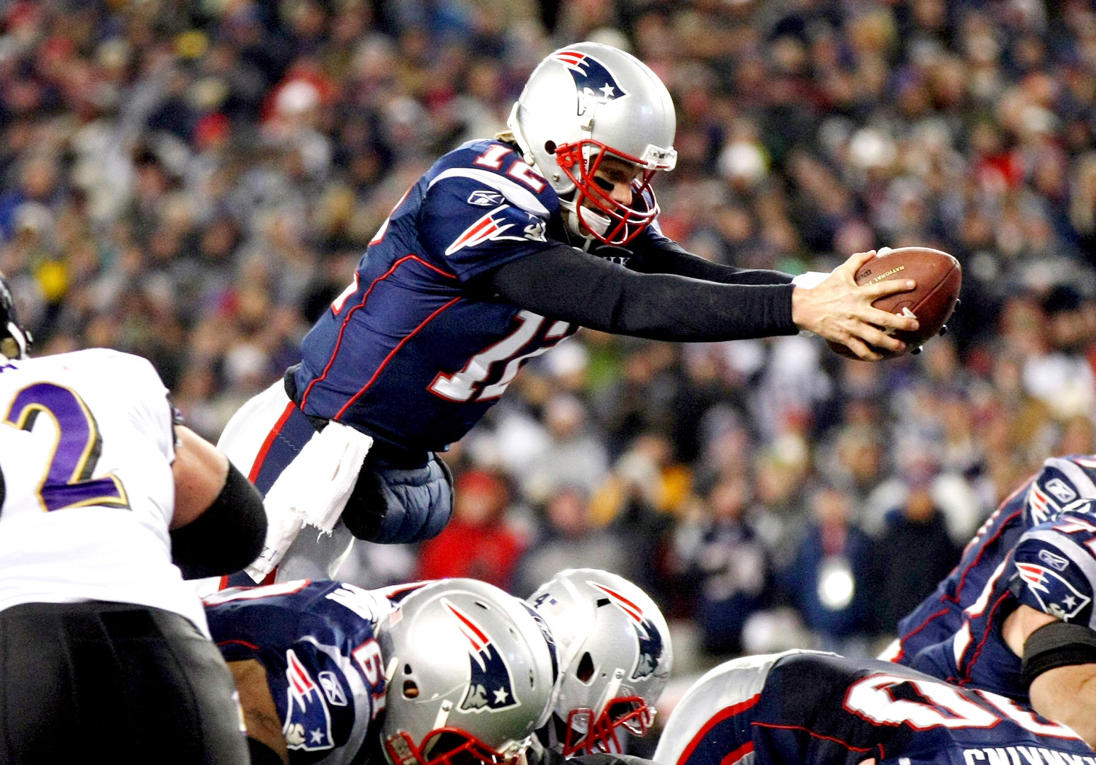 American Football player diving over multiple players for a touch down.