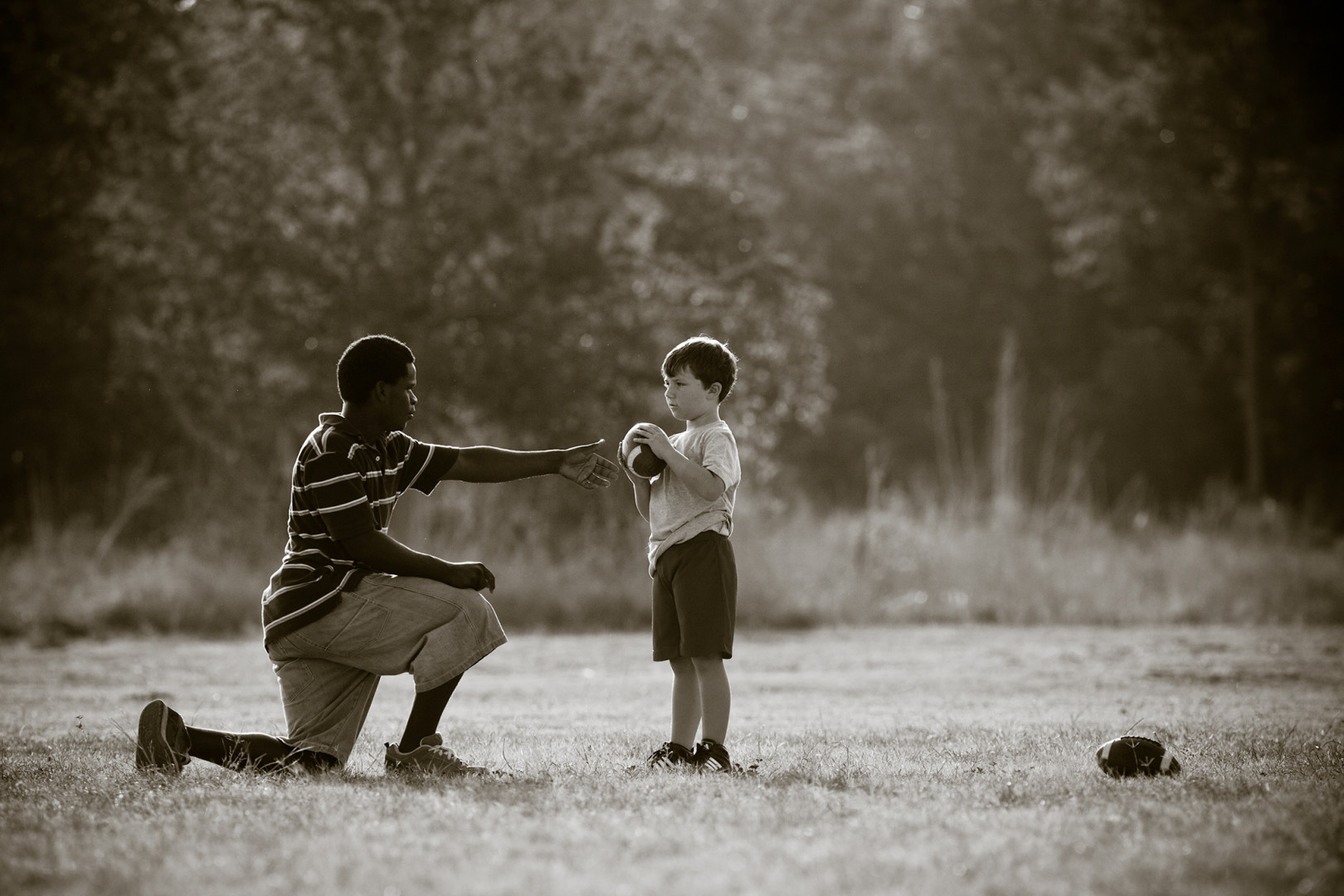 Man coaching young boy on how to play American Football.