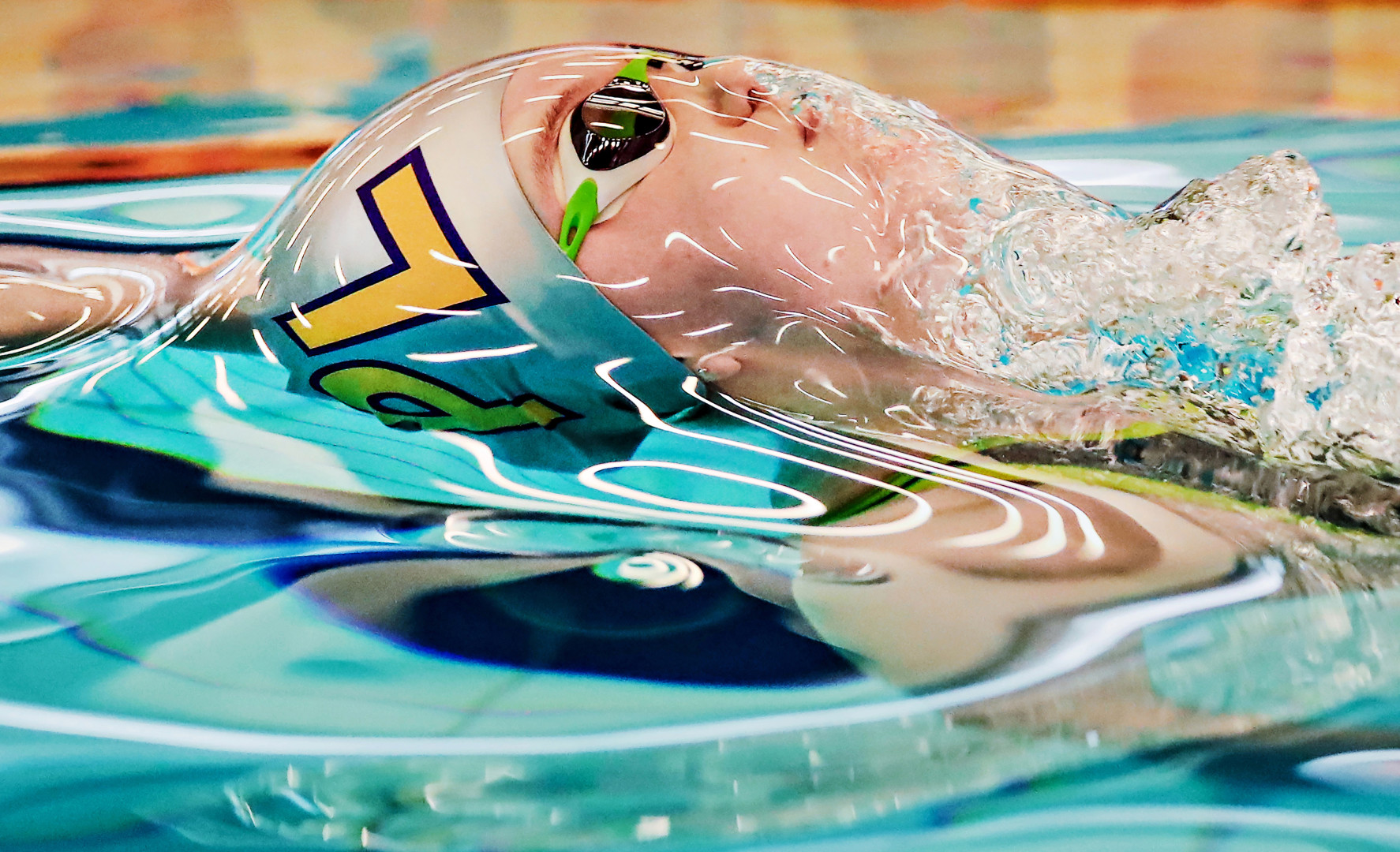 Swimmer engulfed in water as they surface for air during race.