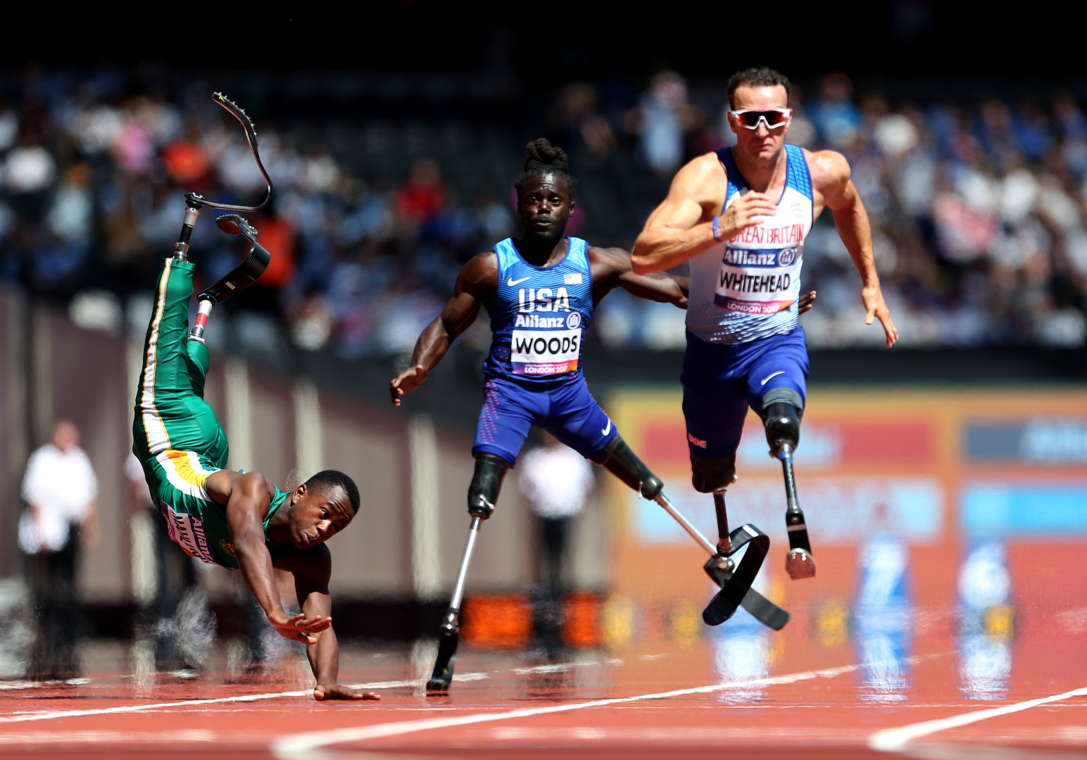 Paralympic runner, Richard Whitehead, wins race as fellow competitor falls head first to the ground as his body is flung in the air.