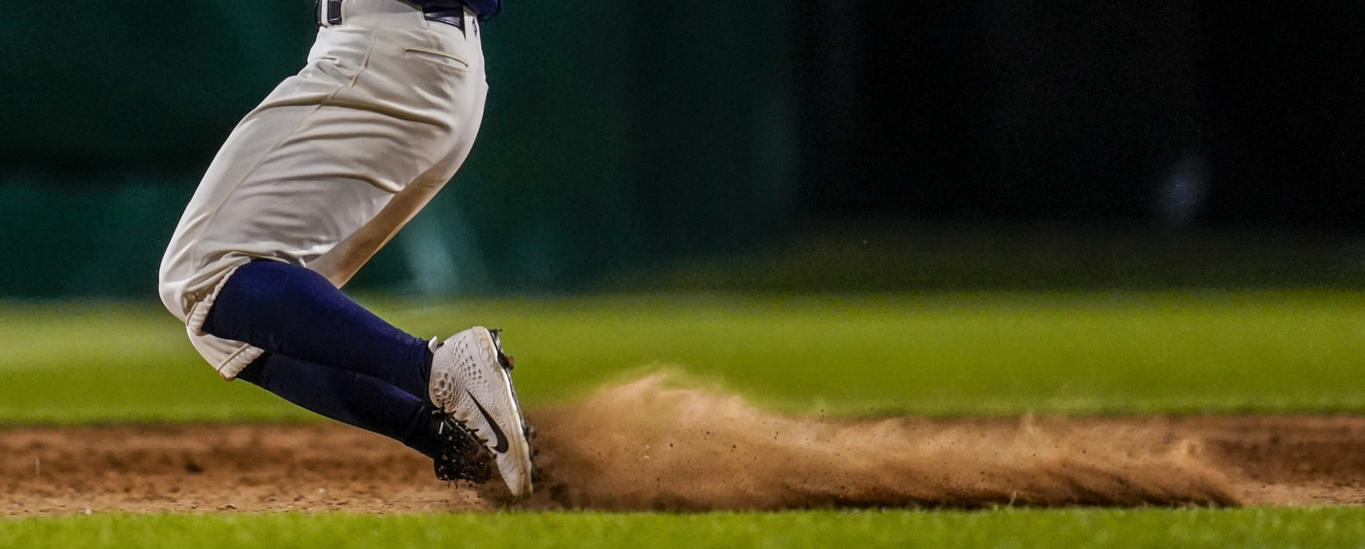 Player mid knee slide on the pitch as mud and dirt spray from his shoes.