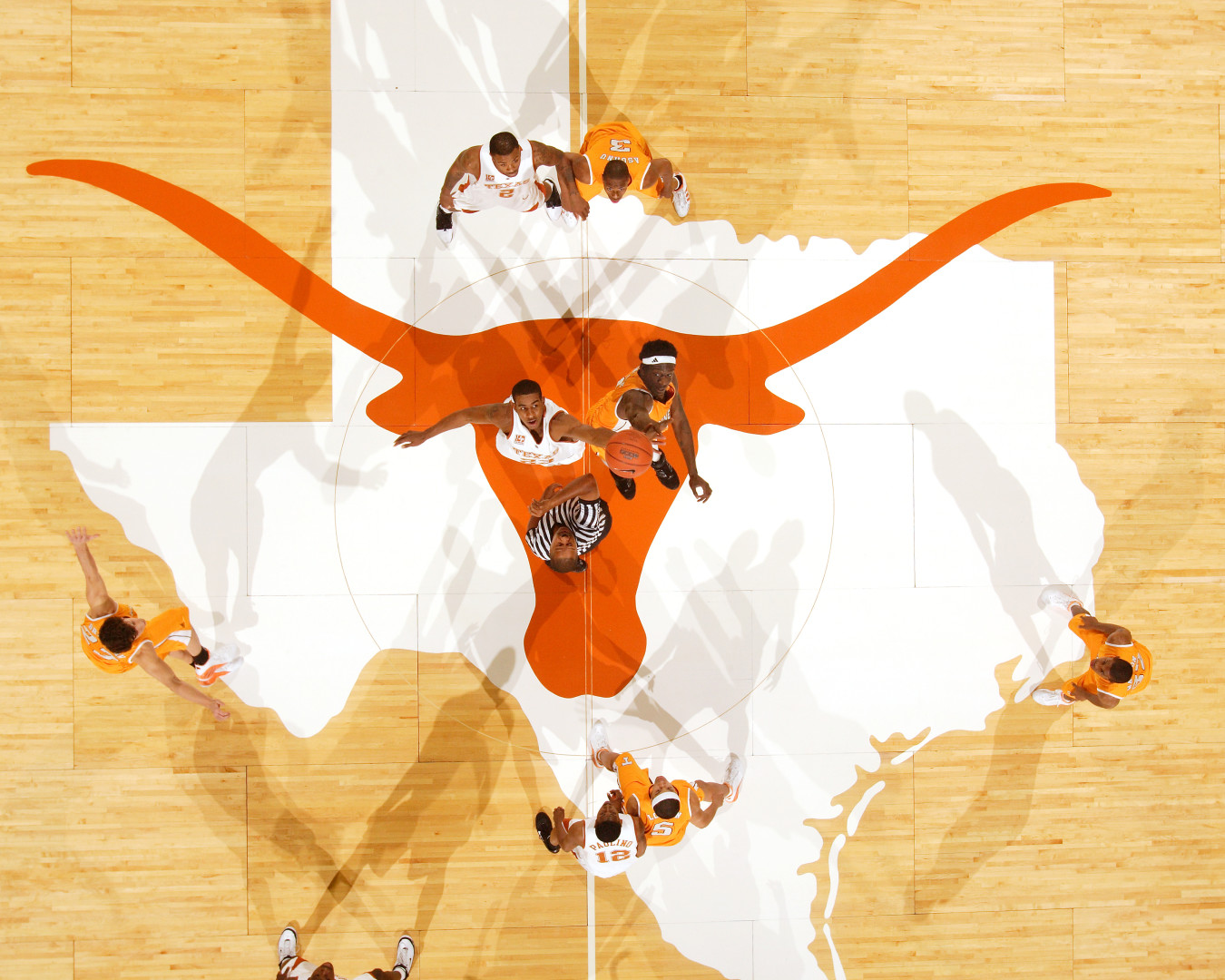 Birdseye view of Texas basketball court as players jump for the ball at the start of the game.