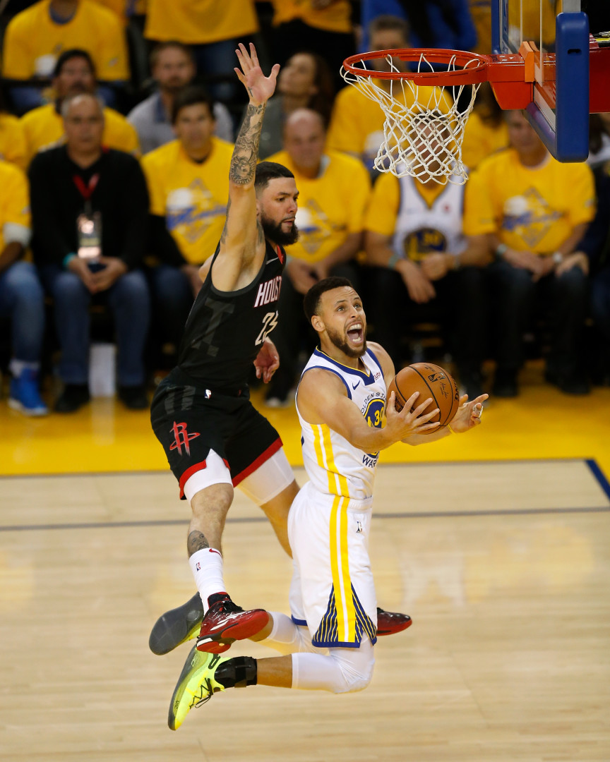 Stephen Curry mid slam dunk as Houston Rockets player attempts block.