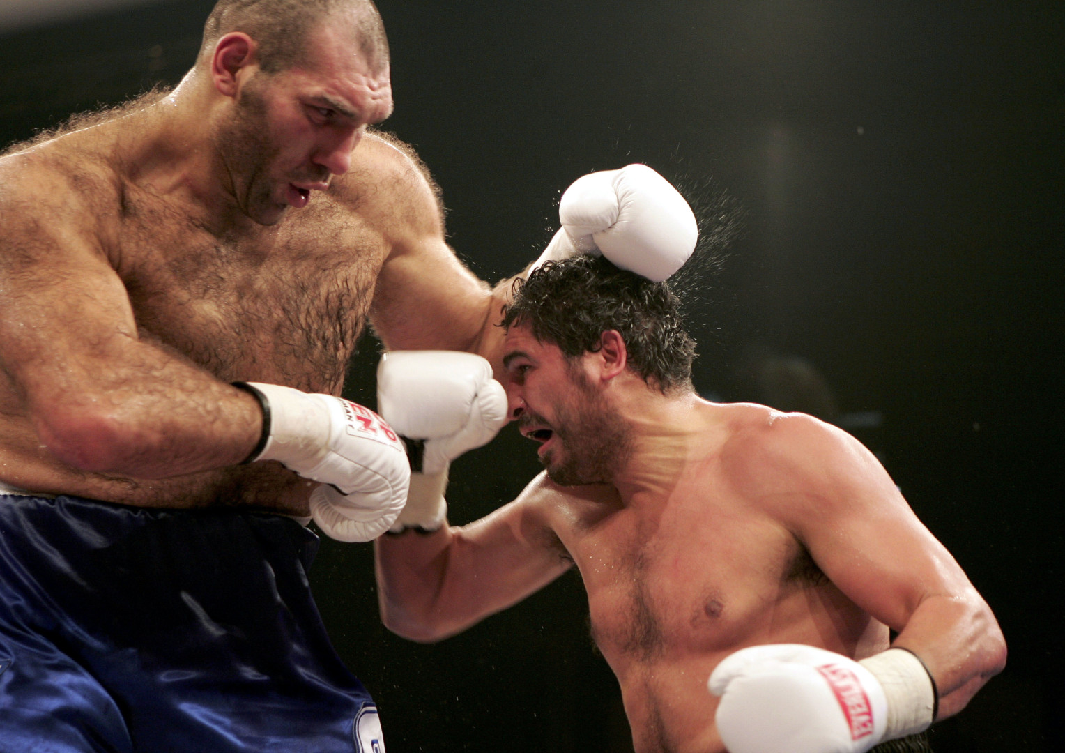 Small boxer attempting hit on  Nikolai Valuev during match.