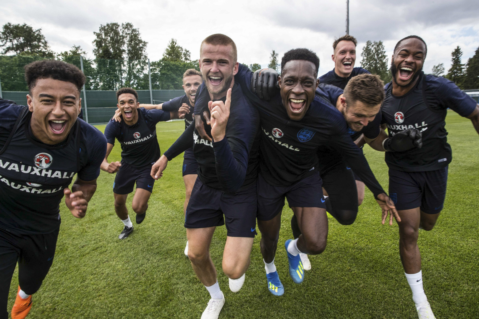 England Men's football players racing to the camera with big smiles.