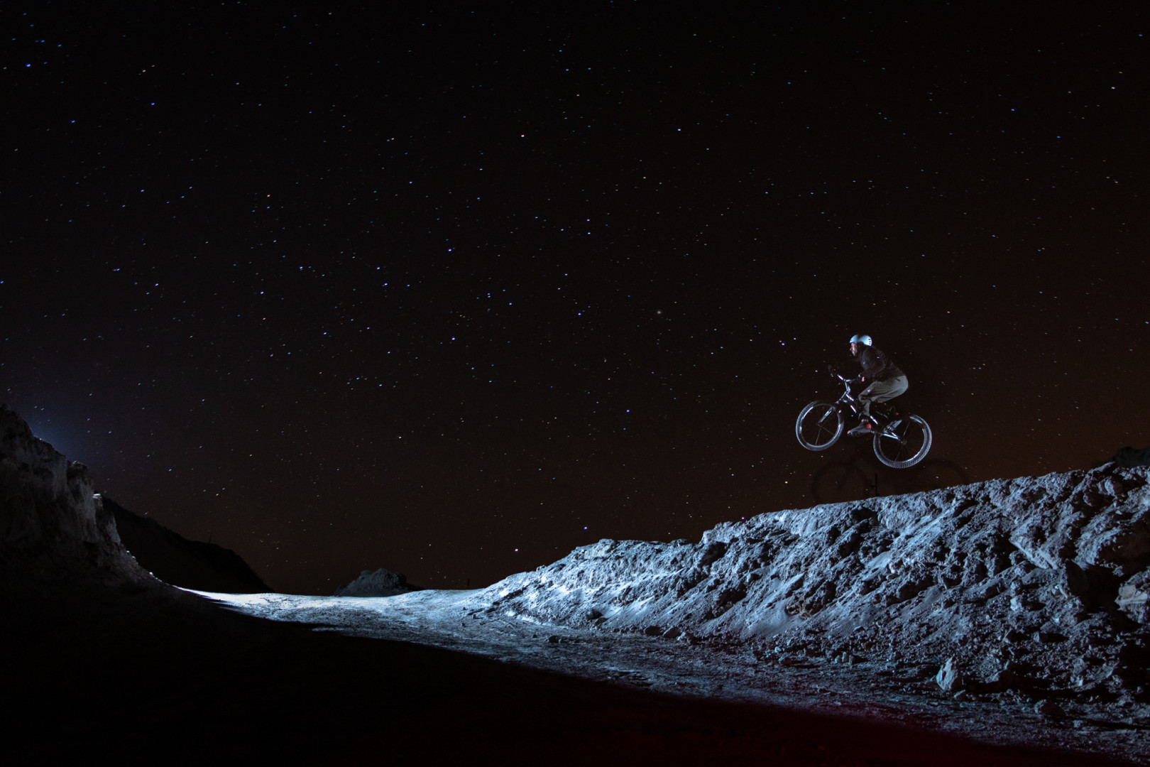 BMX rider jumping off a quarry cliff that looks like the moon.