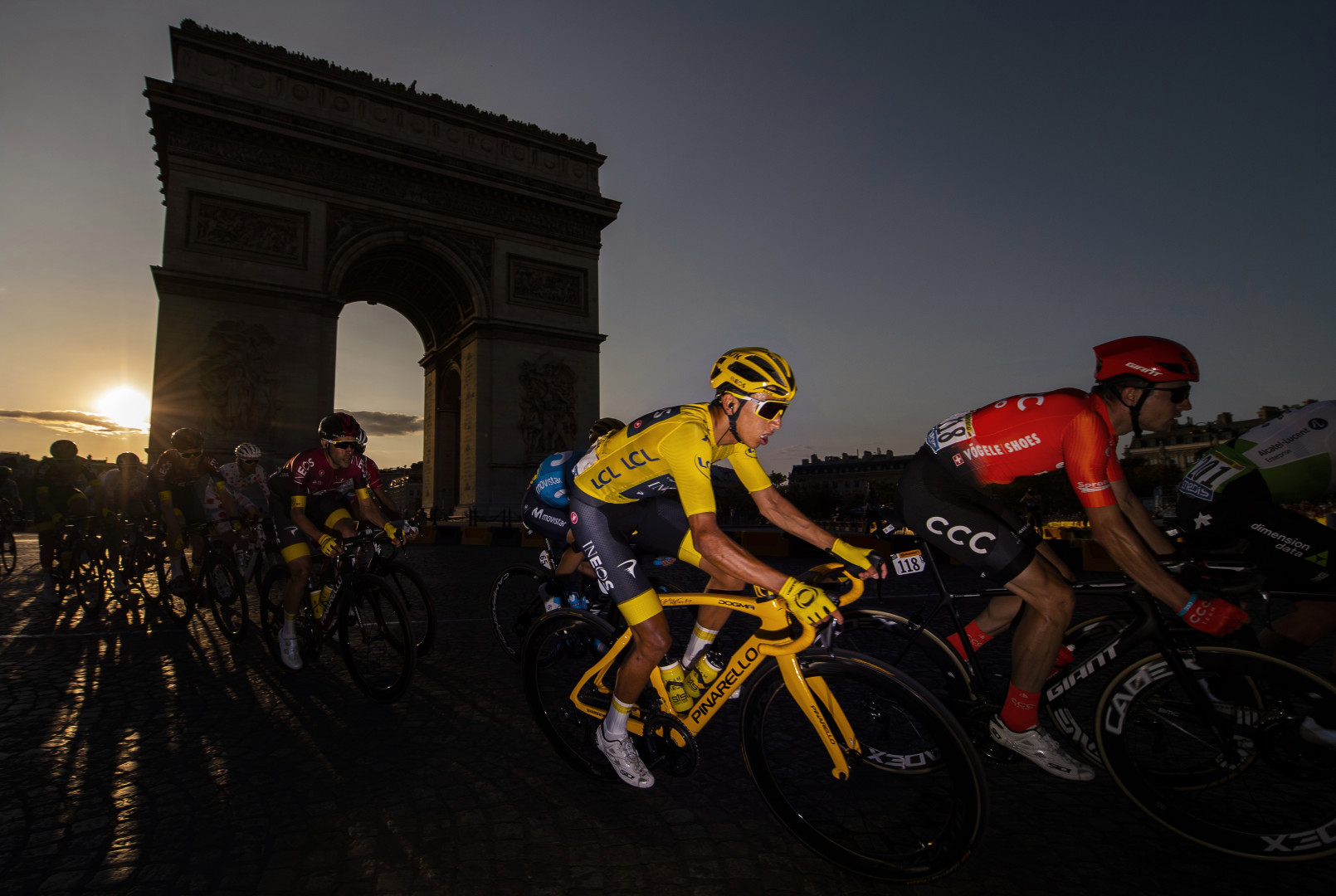 Tour de France cyclists riding past the Arc de Triomphe.