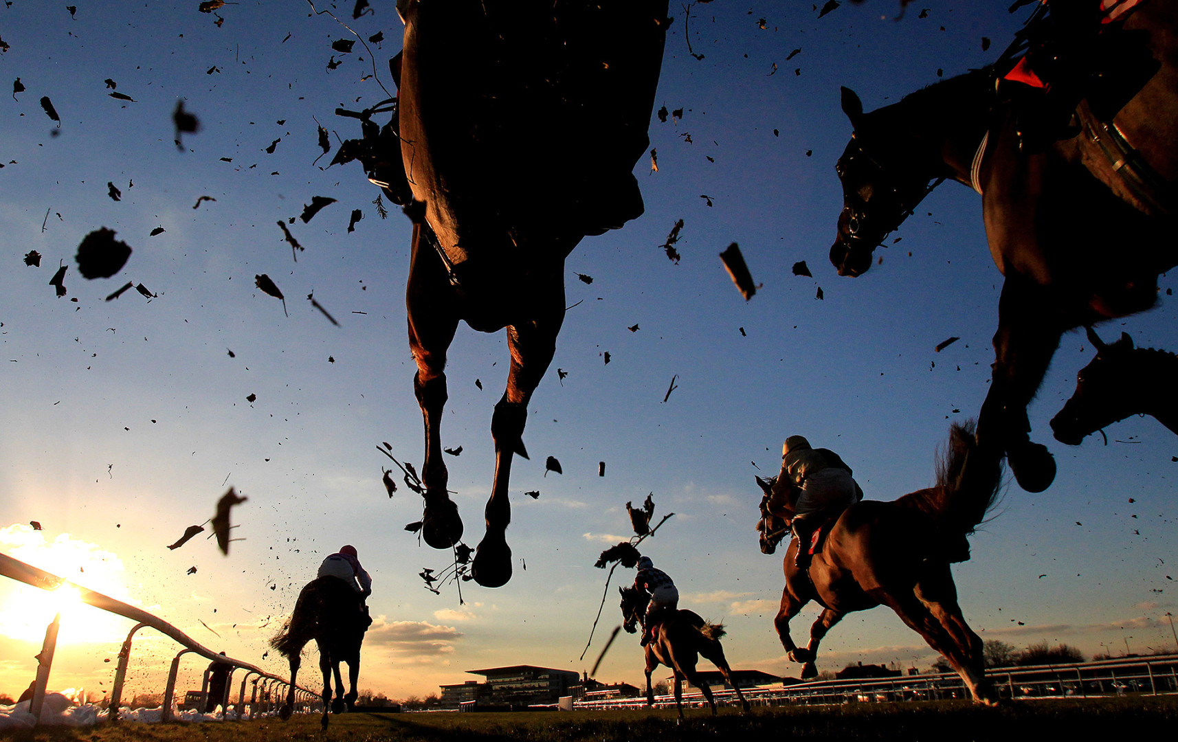 Horses jumping over camera in sunset shot as grass and mud is flung around.