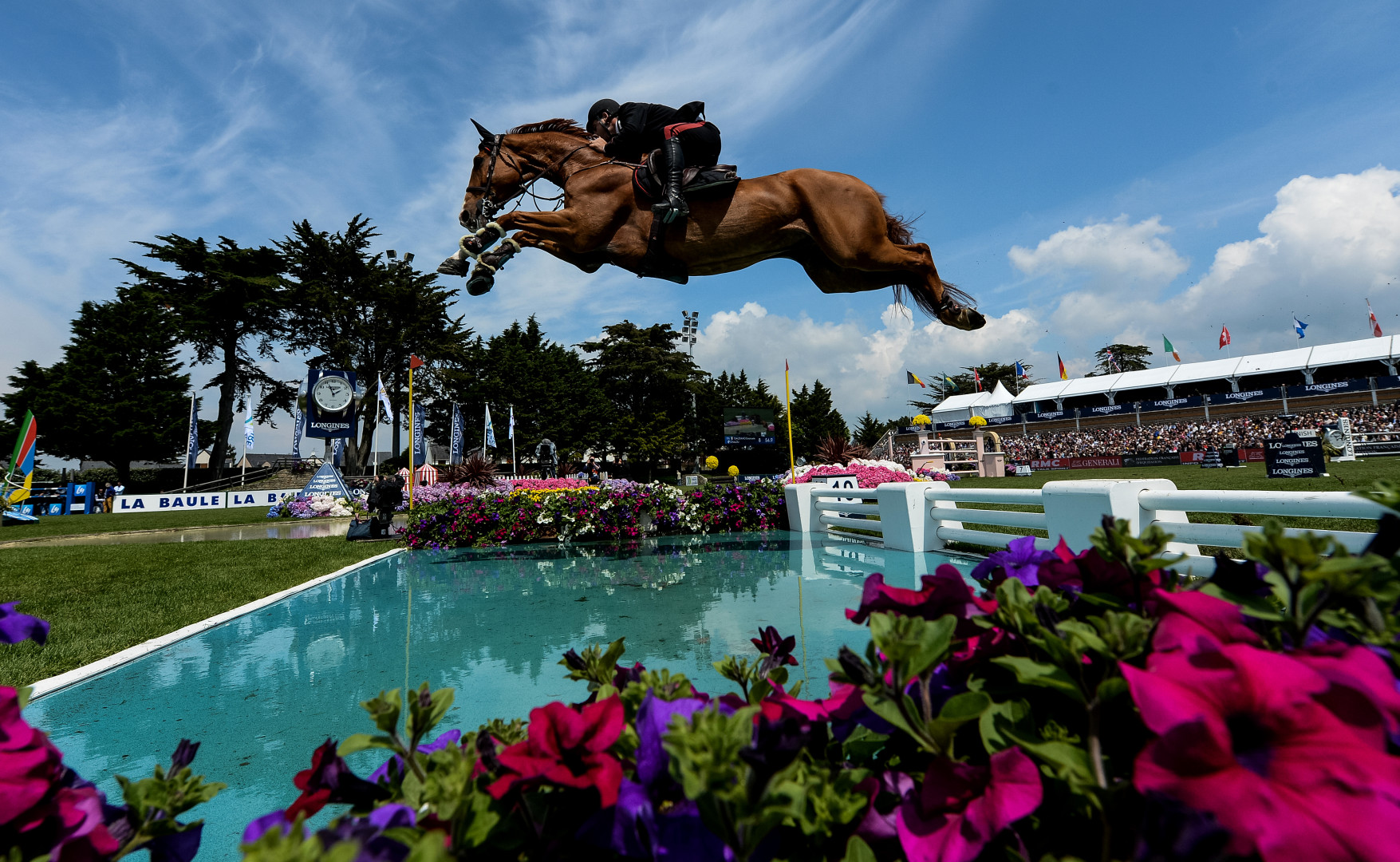 Horse & rider jumping over water in show jumping competition.