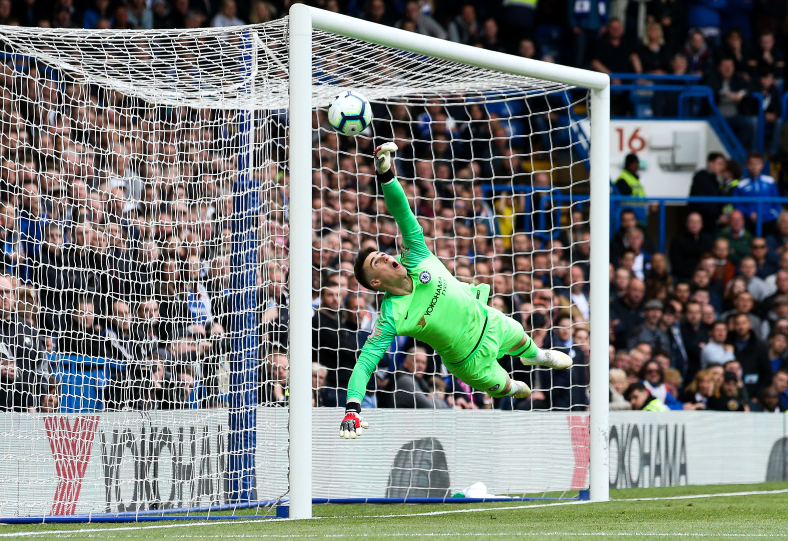 Kepa Arrizabalaga stretching across the goal to punch the ball away from goal. 