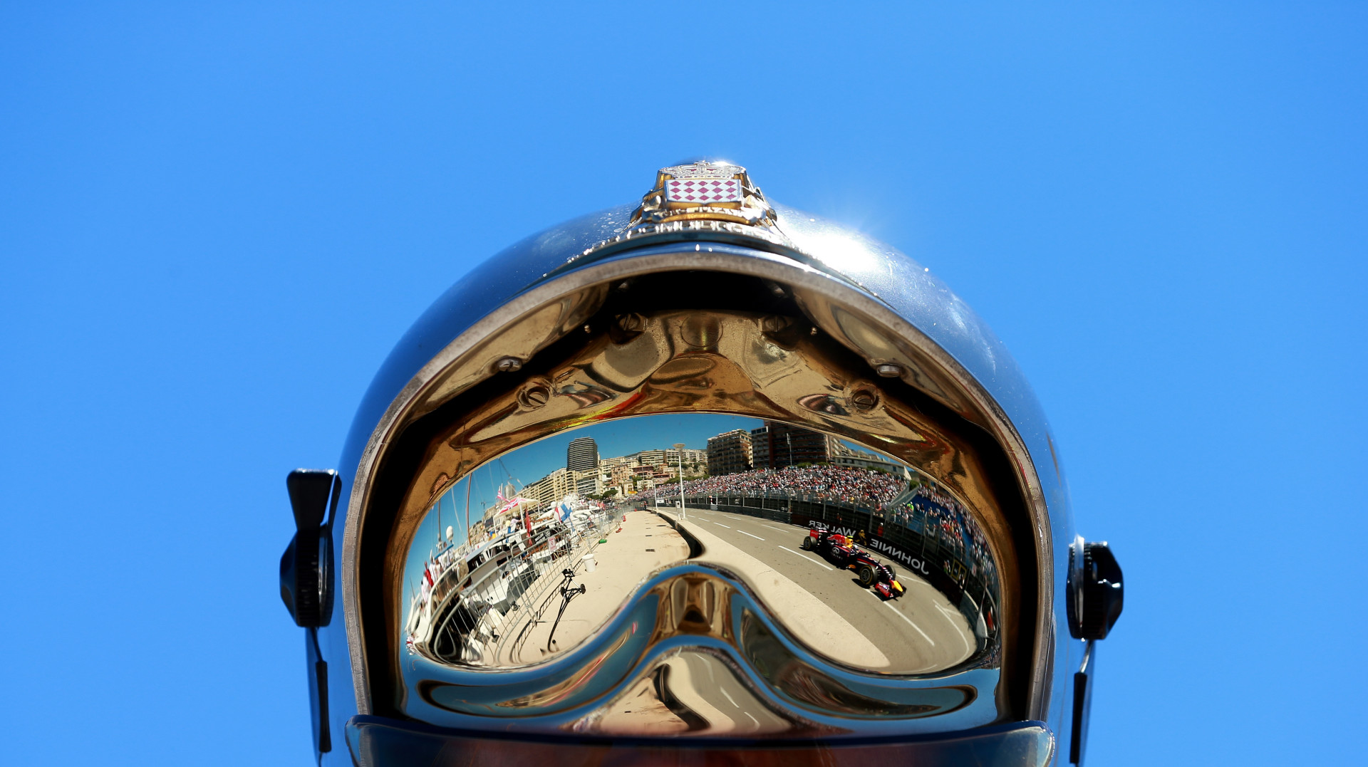 Views of the Monaco Grand Prix track through a reflection of a helmet statue.