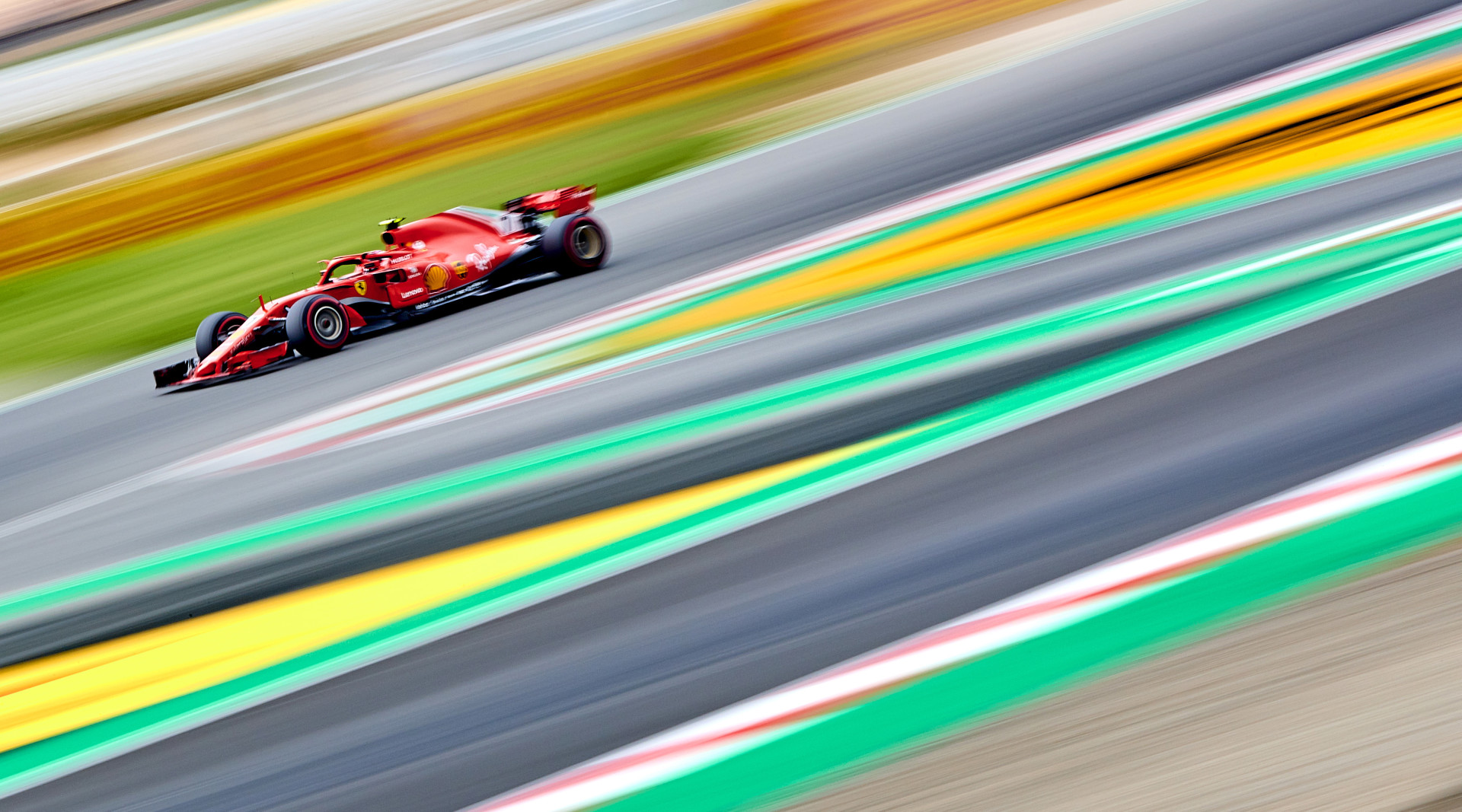 Action shot of a formula 1 race car racing around the track as the track blurs into lines and colours.
