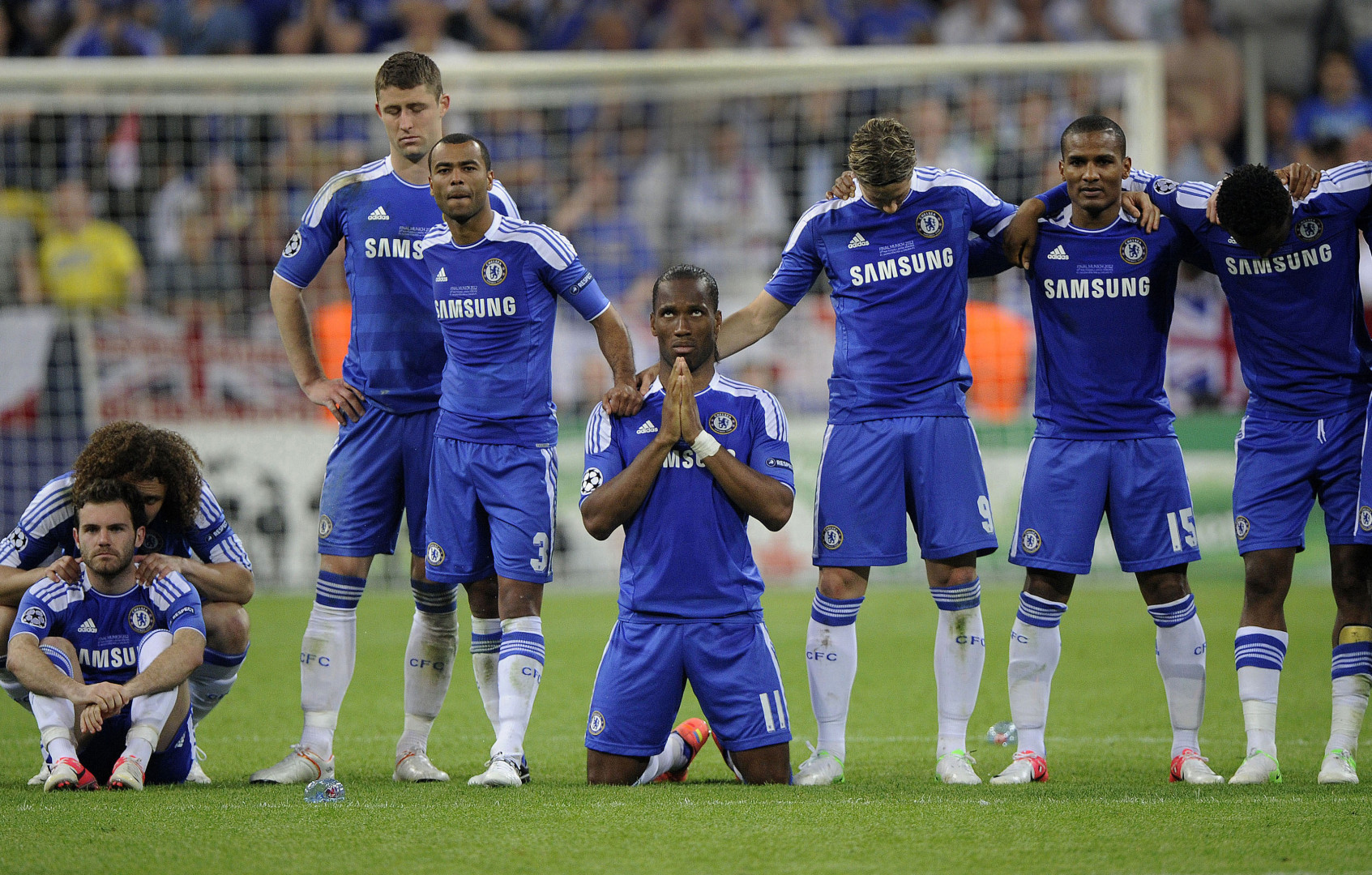 Didier Drogba praying in a line of Chelsea football players during a Champions League final shoot-out.