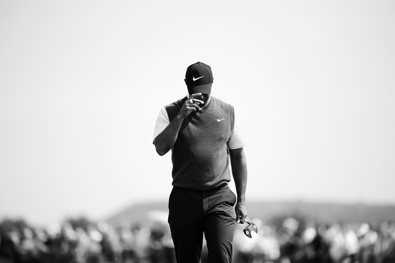 Black & White photograph of golfer player tipping his cap to cover his face.