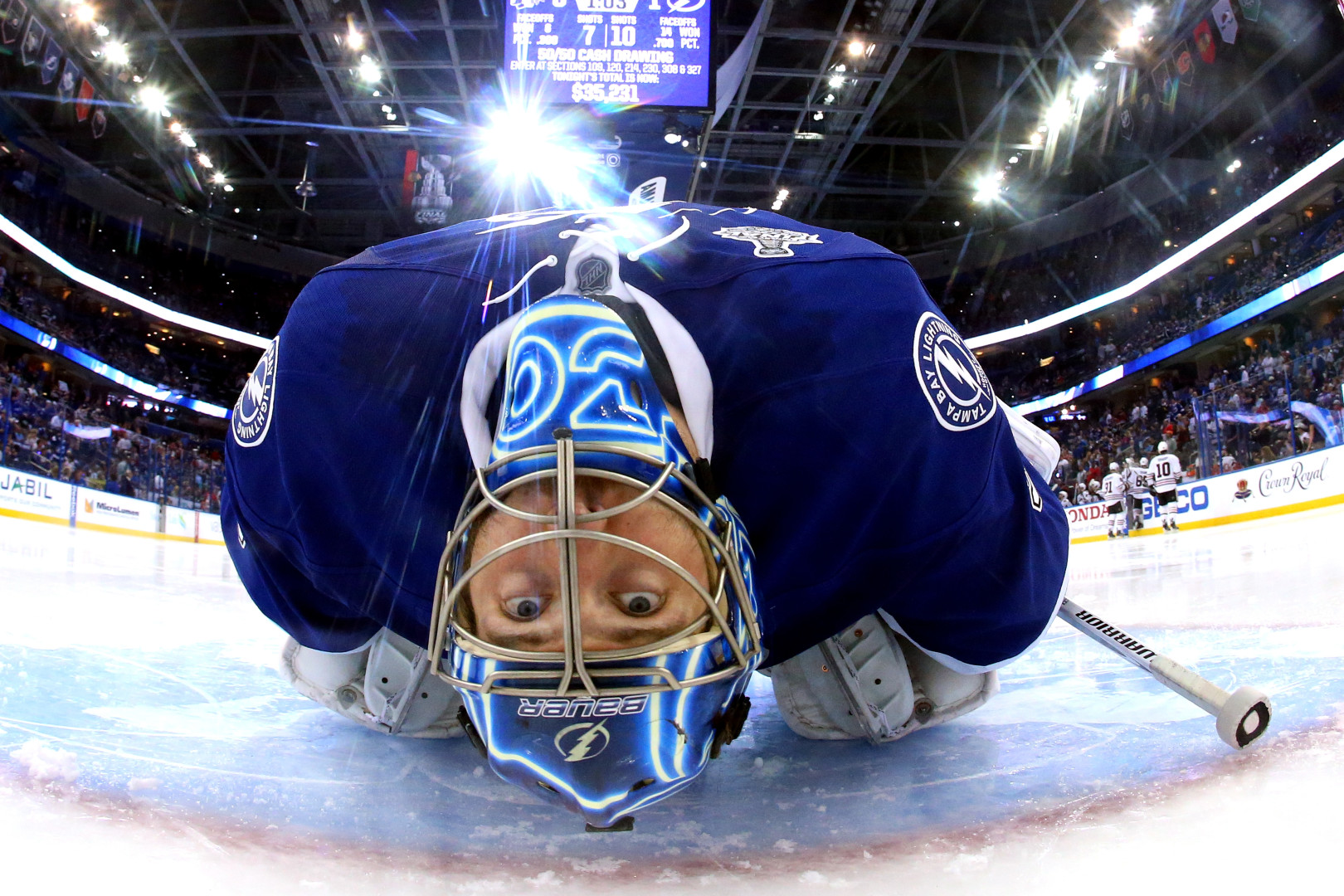 Fisheye photograph of a Ice Hockey player lying on the floor looking into the lens of the camera.