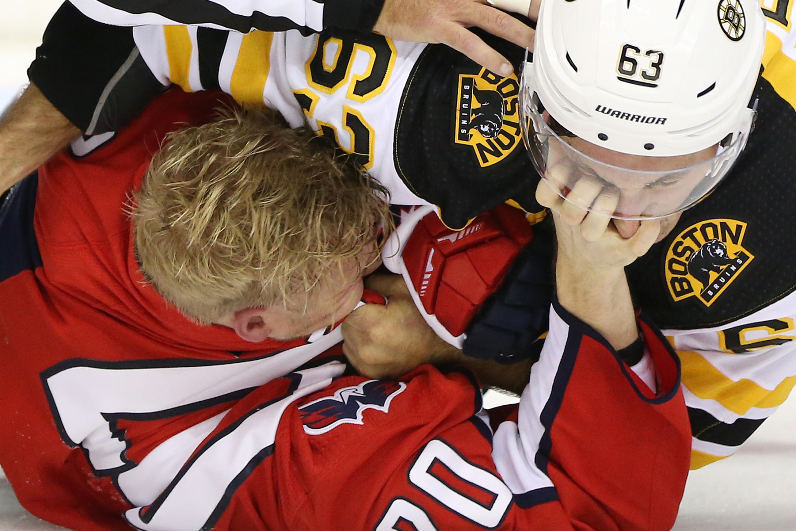 Close up of ice hockey player scratching opposition player's eye in scrap during game.