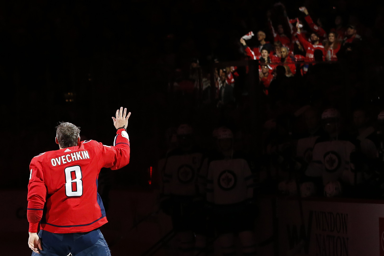 Spotlight on Overchkin as he waves to fans in the ice rink stands.