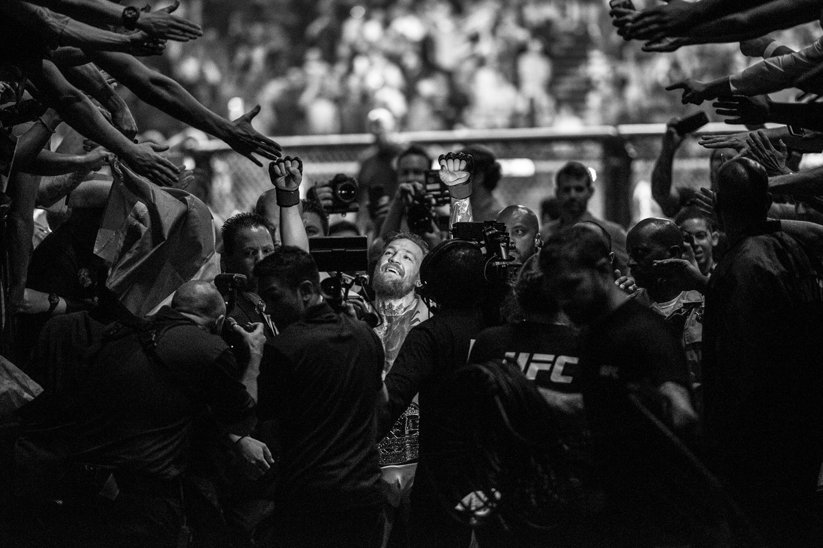 Black & White image of kick-boxing champion surrounded by fans and photographers.
