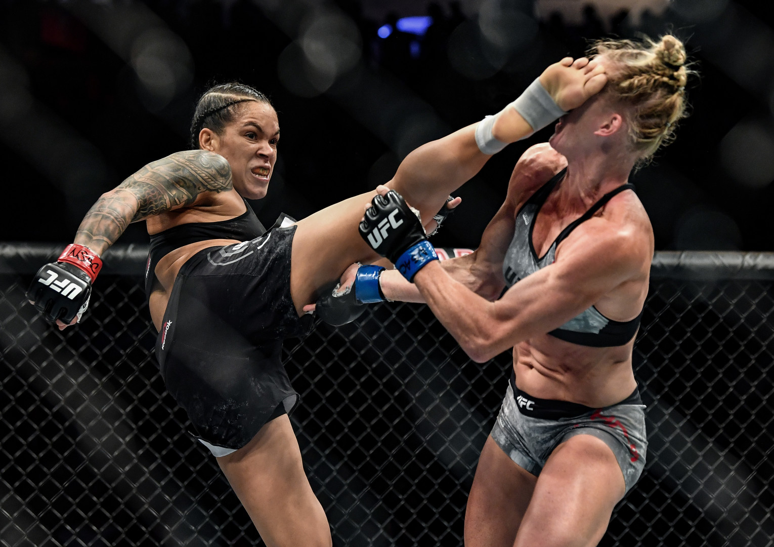 Female UFC fighter receiving a kick to the head during fight.