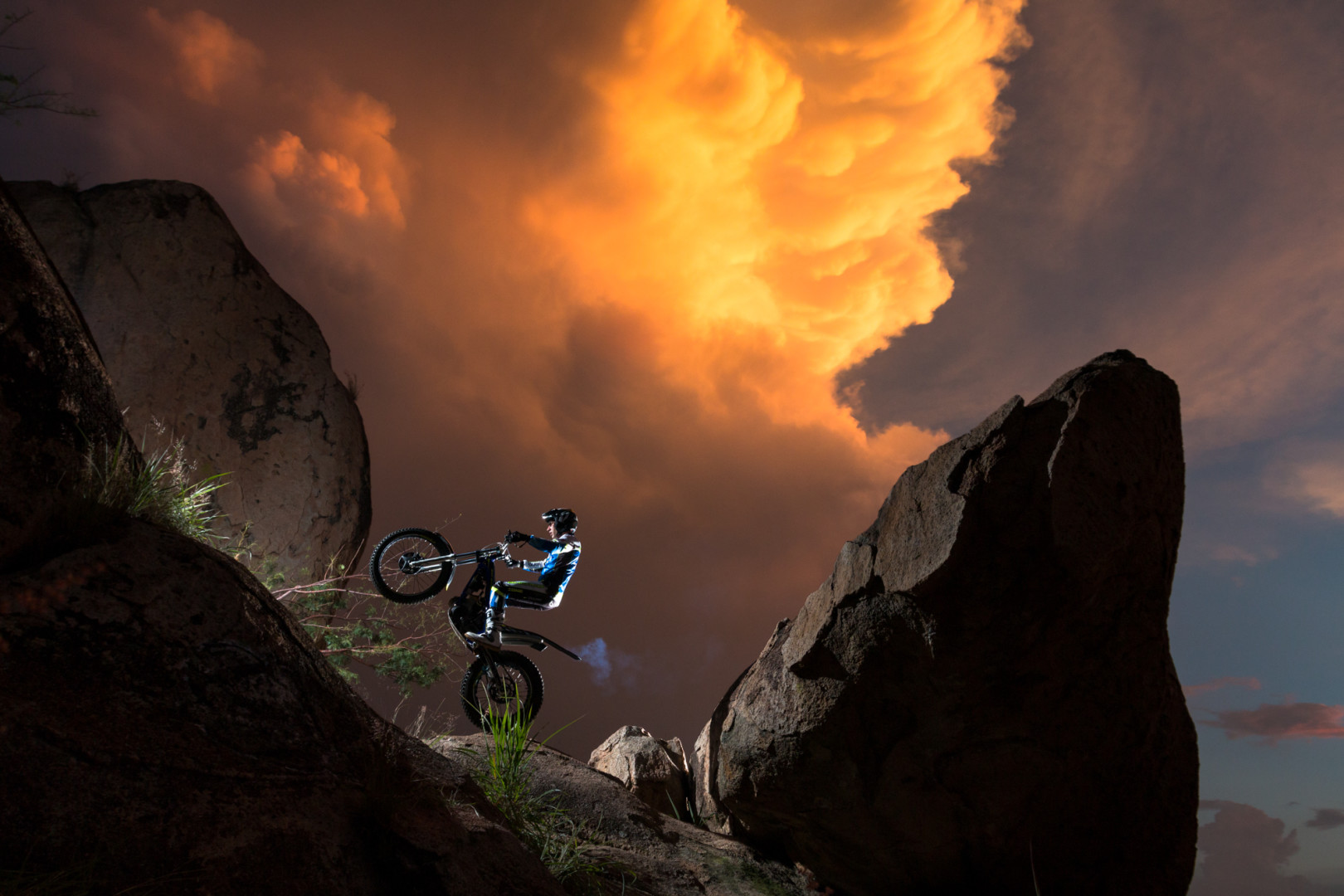 Motorcyclist balancing on their back wheel on rocky terrain. 