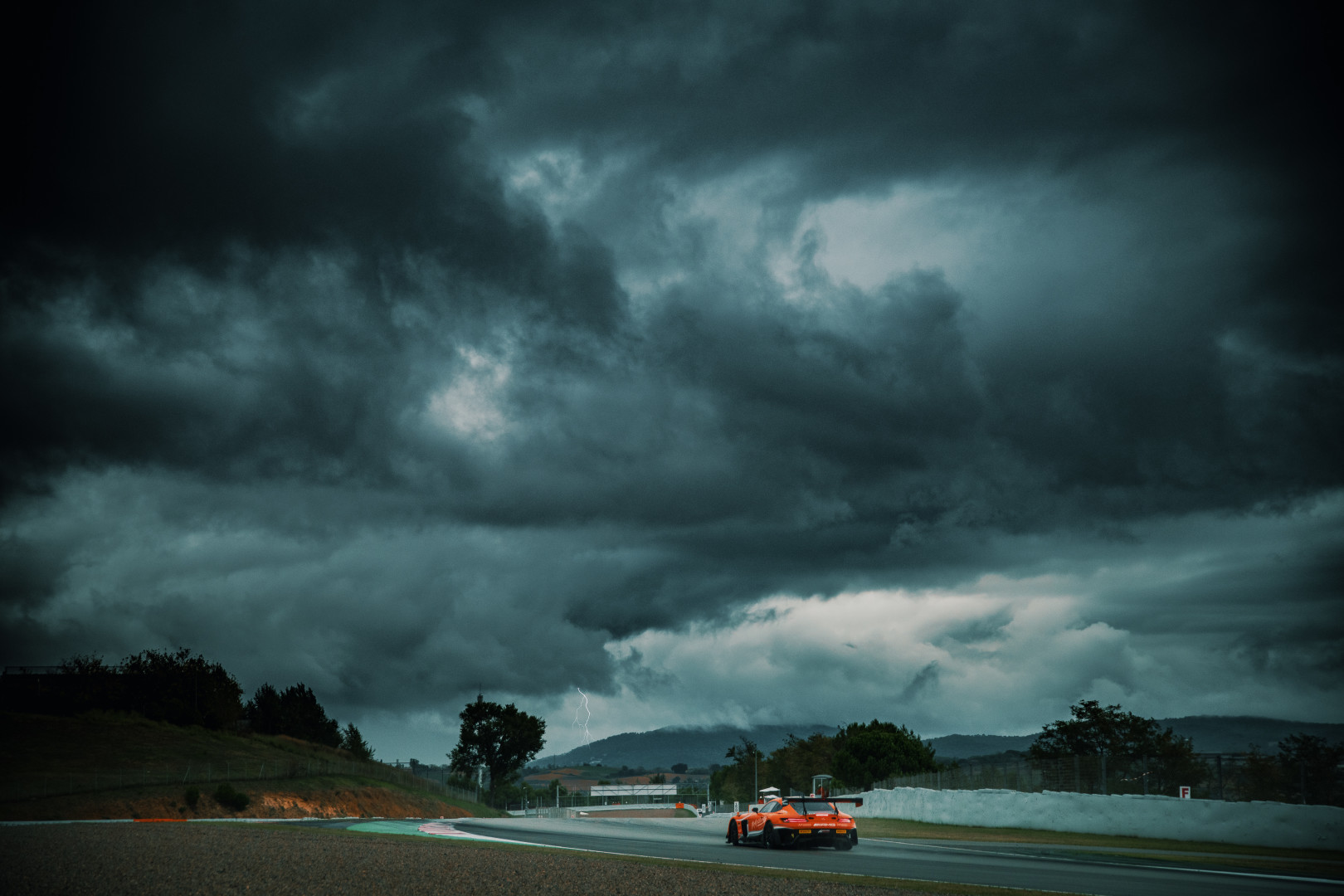 Motorcar travelling around the Catalunya circuit in stormy conditions.