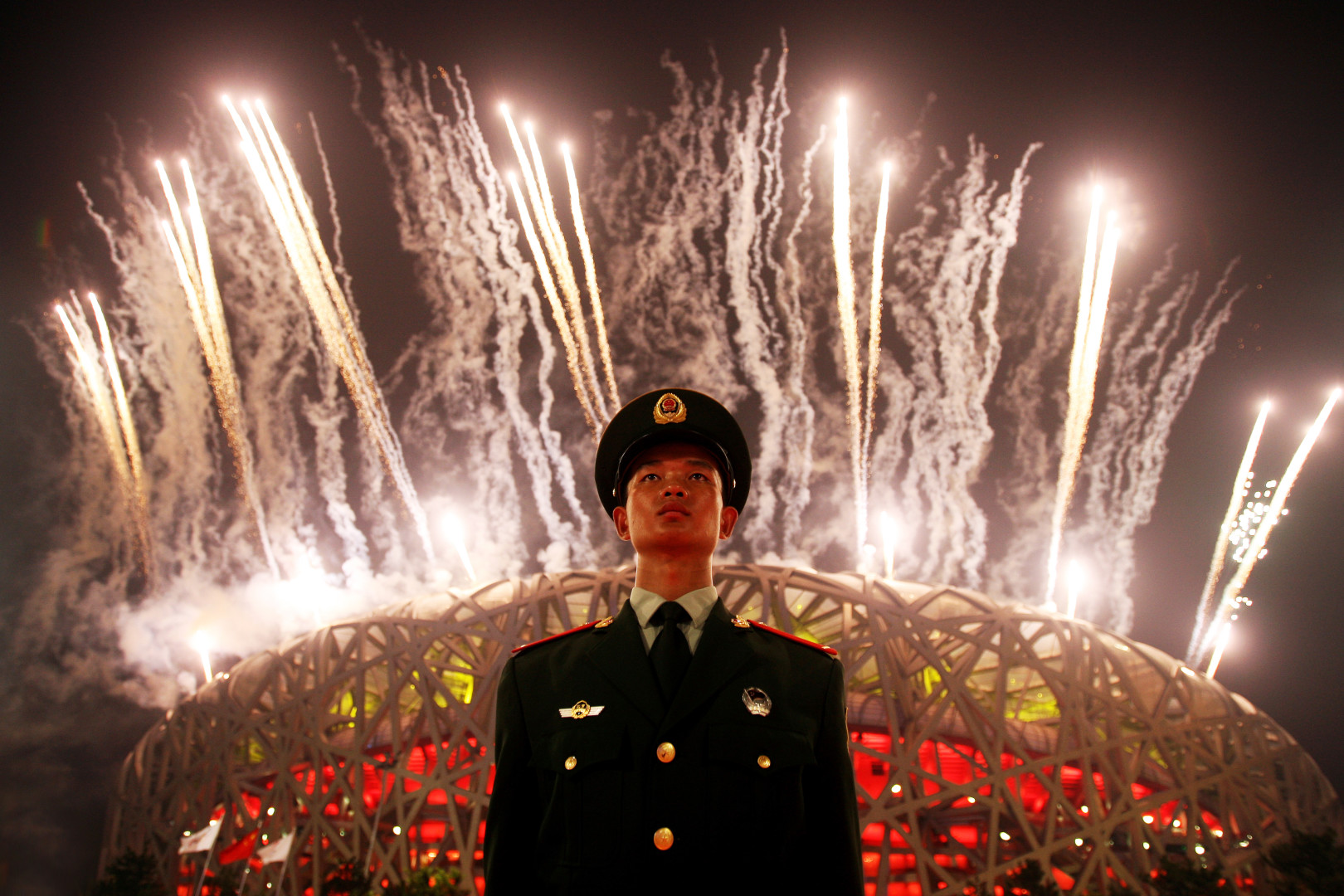 Armed Force soldier stood guarding as fireworks go off in the Bird's Nest Stadium in Beijing.