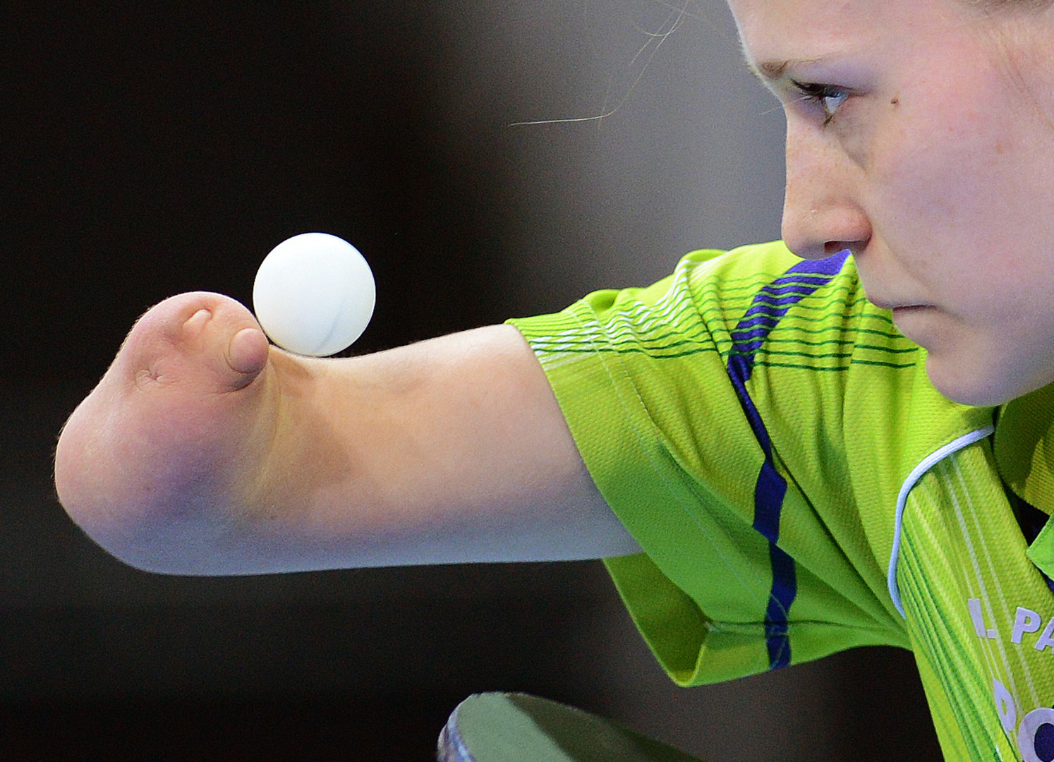 Paralympic table tennis competitor poised in position as ball sits on her arm before she starts the game.