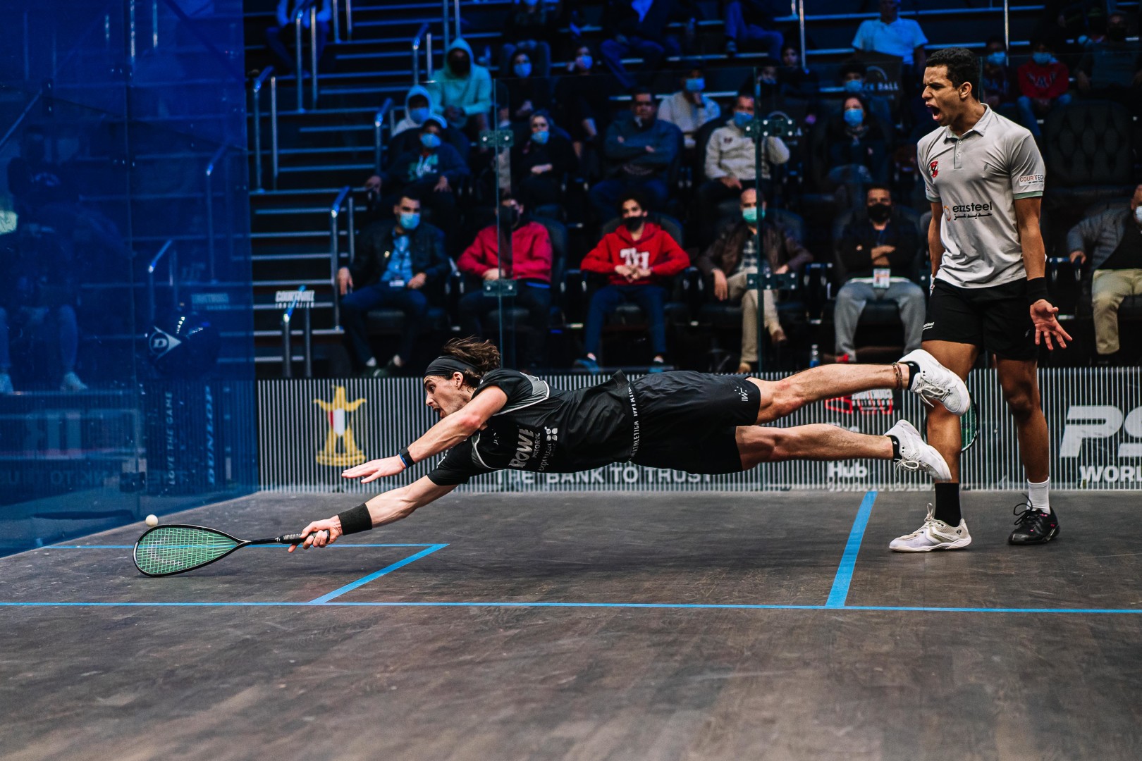 Squash player desperately dives in order to get shot on the court.
