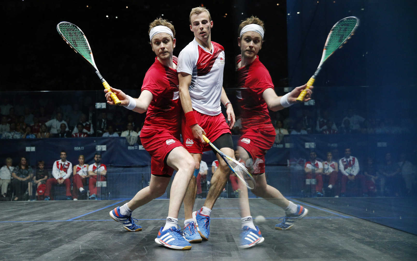 Reflection of squash player as both competitors battle up against the glass.