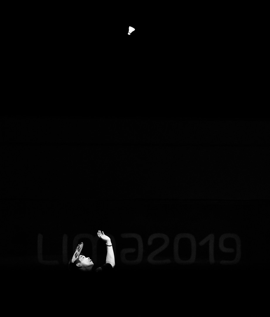 Black & White image of the light catching Nyl Yakura making a serve in a badminton match.