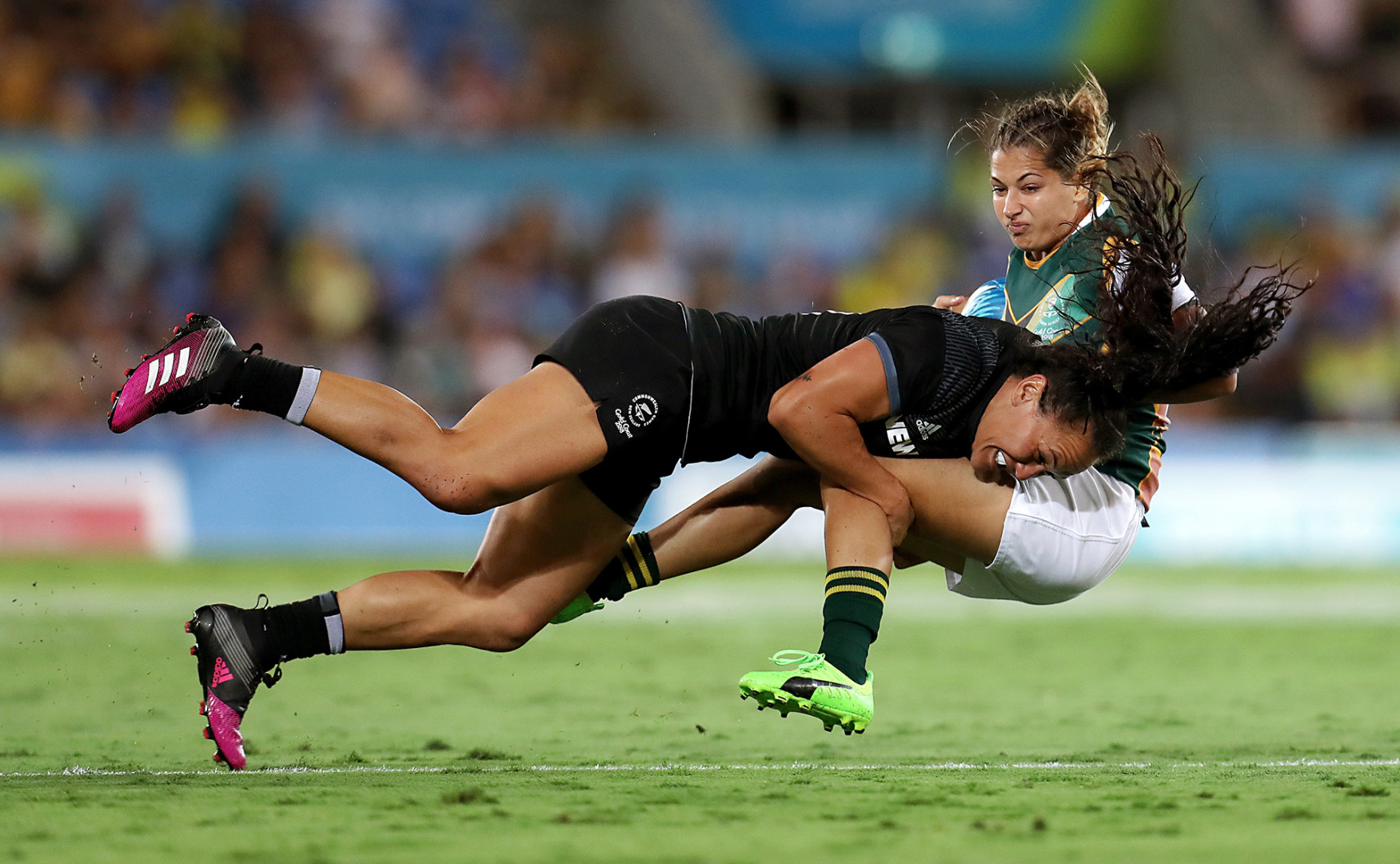 Female New Zealand 'All Blacks' lands big tackle on opponent player.