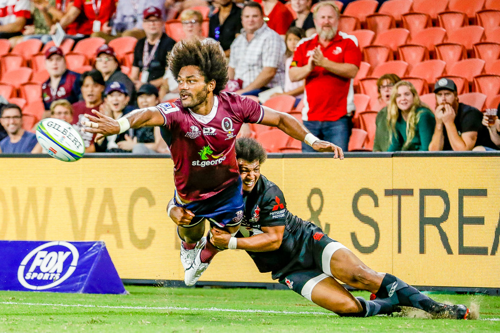 Rugby player offloading ball mid tackle.