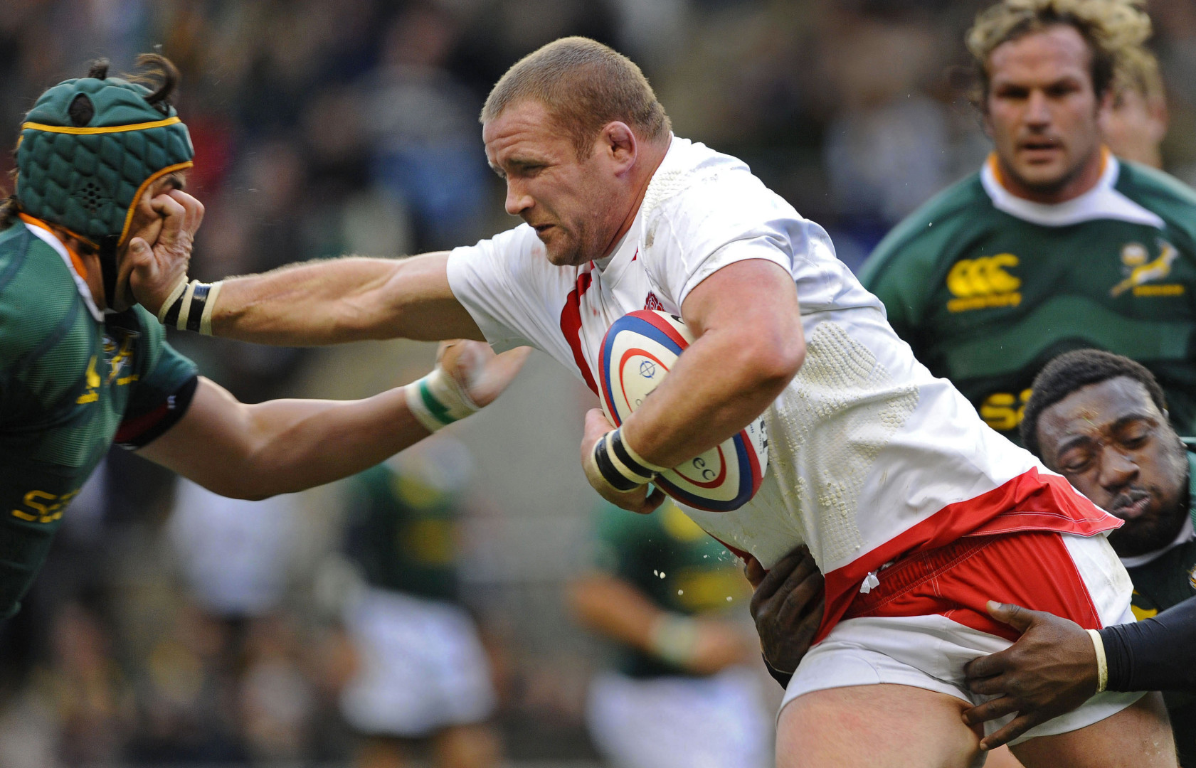 English rugby player face-palming South African player in order to get through defence line.