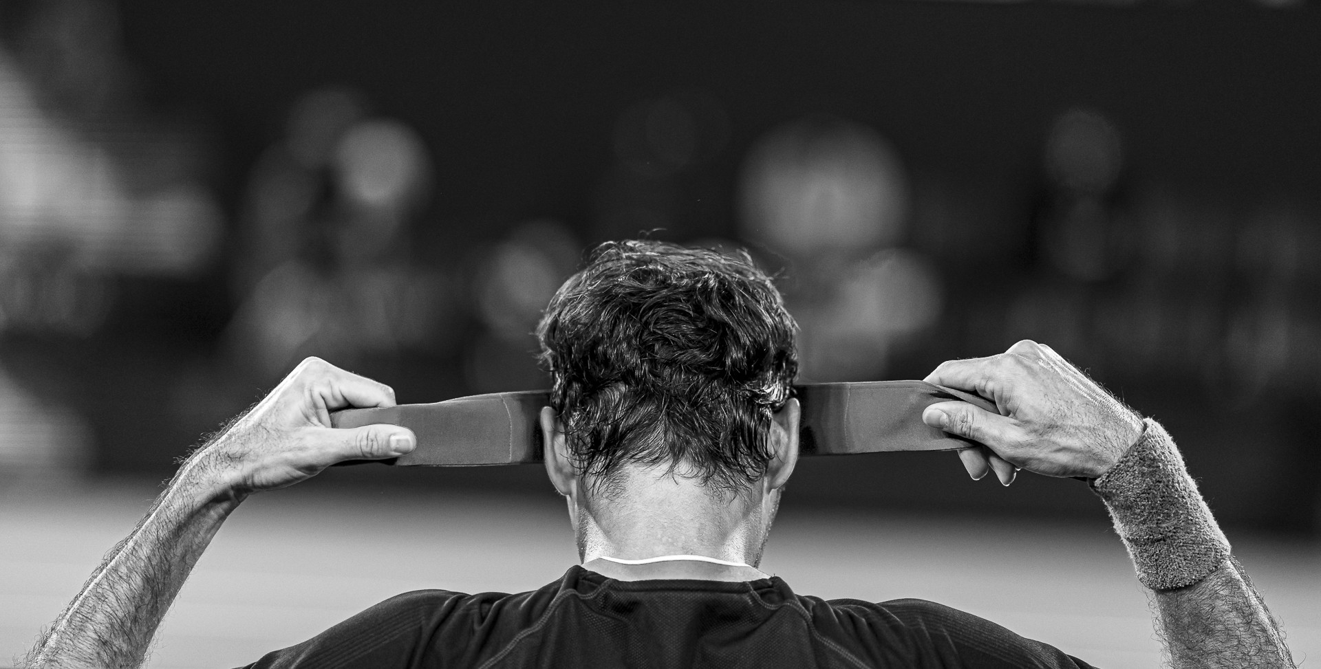 Black & White head shot of Roger Federer putting on a sweat band on his head.