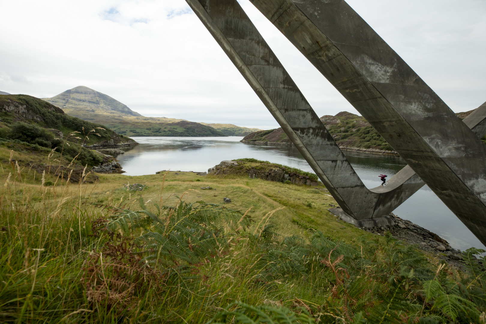 Male skateboarder performing tricks  on a bridge structure by the side of a river.