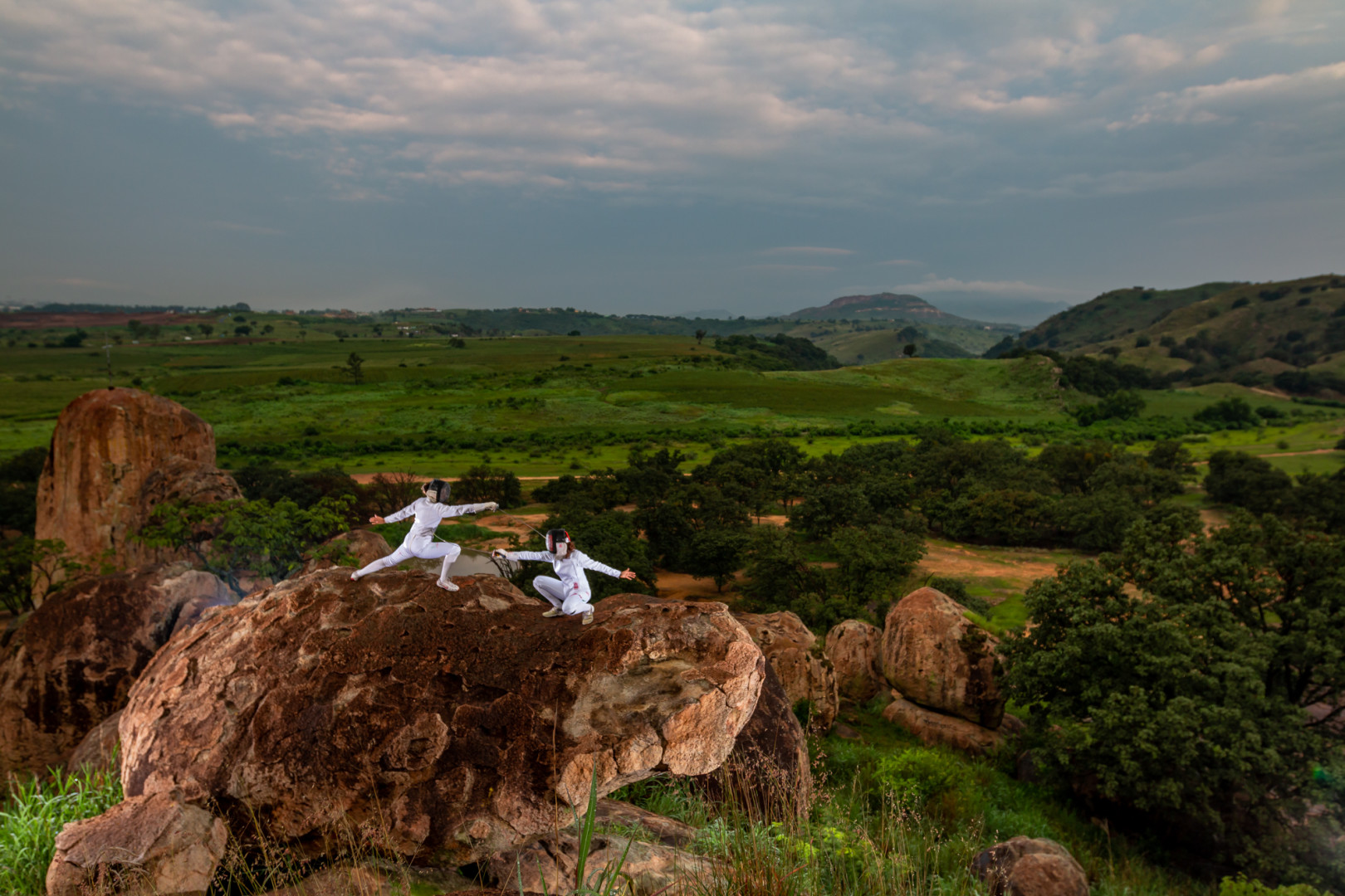 Two female athletes fencing on a boulder in the great outdoors.